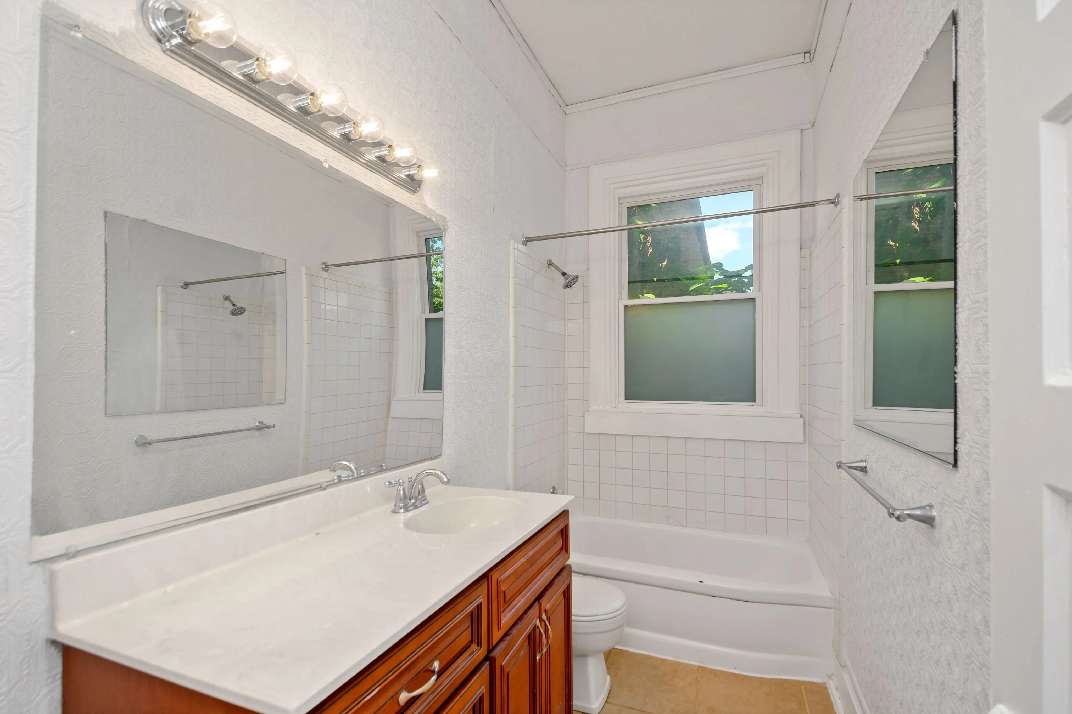 Bright, modern bathroom featuring elegant vanity with mirror and window views.