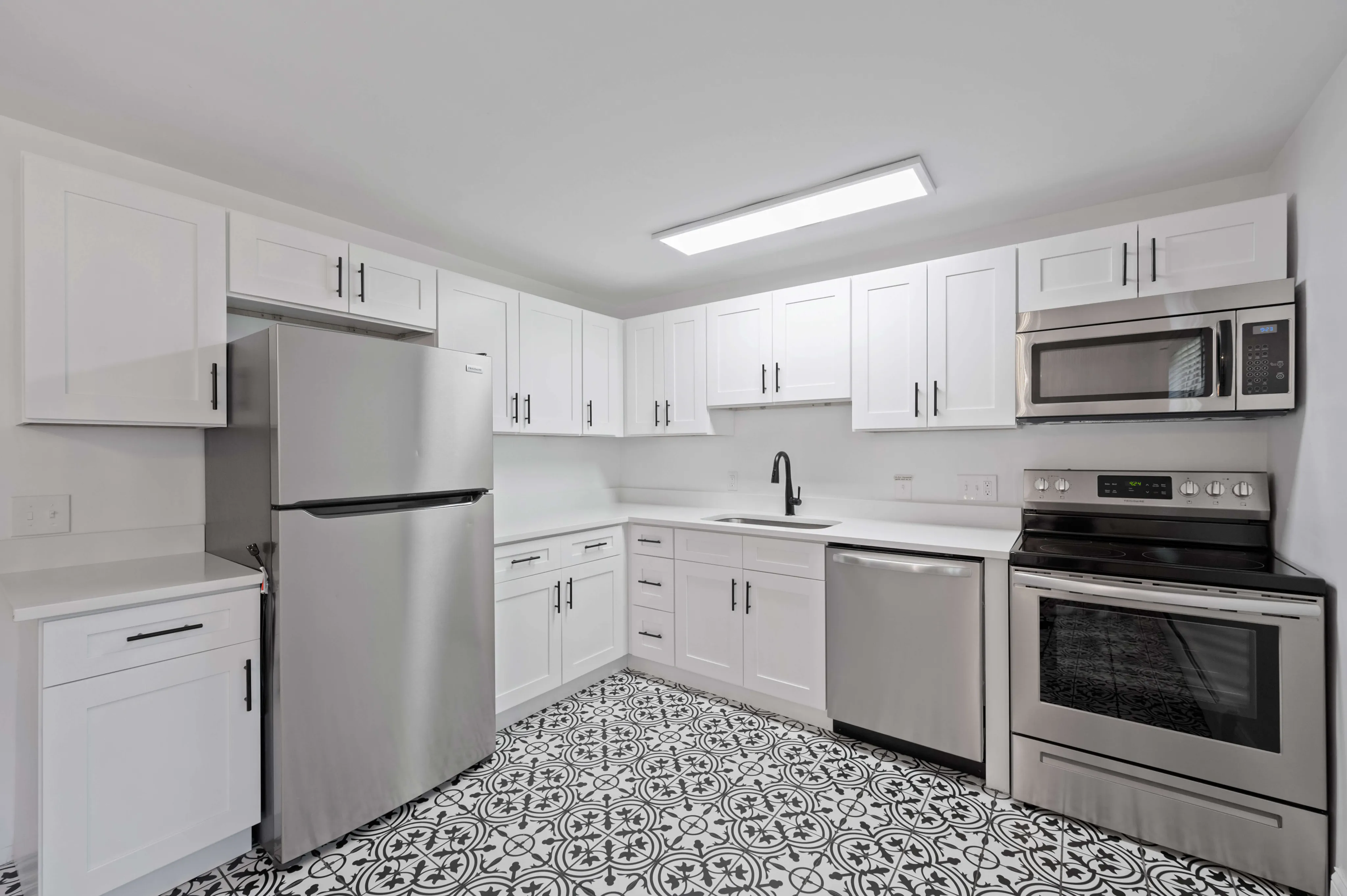 Modern kitchen with stainless steel appliances, elegant white cabinetry, and intricate patterned flooring.