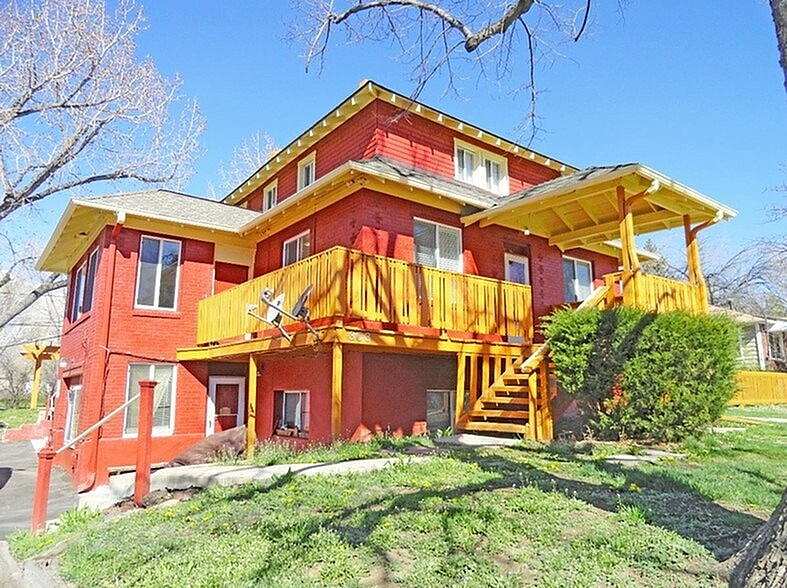 Inviting two-story brick home with warm wooden accents and a sunny porch.