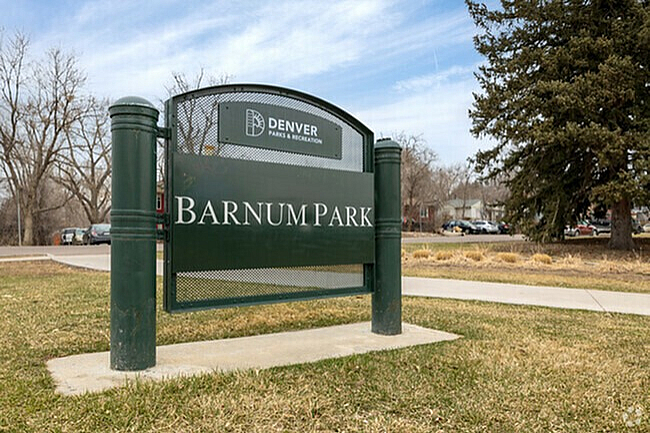 Barnum Park entrance sign in Denver, surrounded by grass and trees.