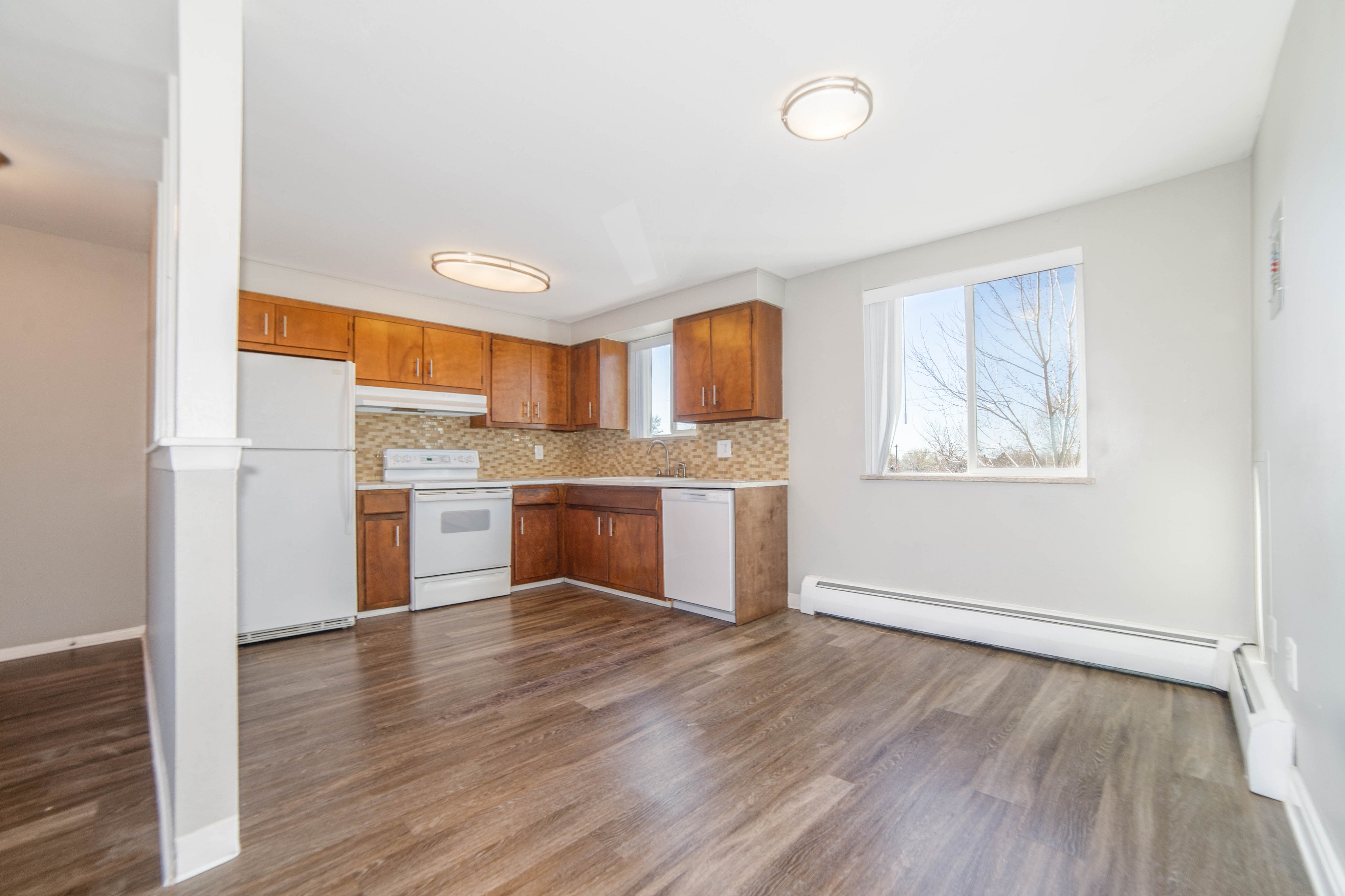 Bright and airy kitchen with modern wooden cabinetry, sleek appliances, and large window for natural light.