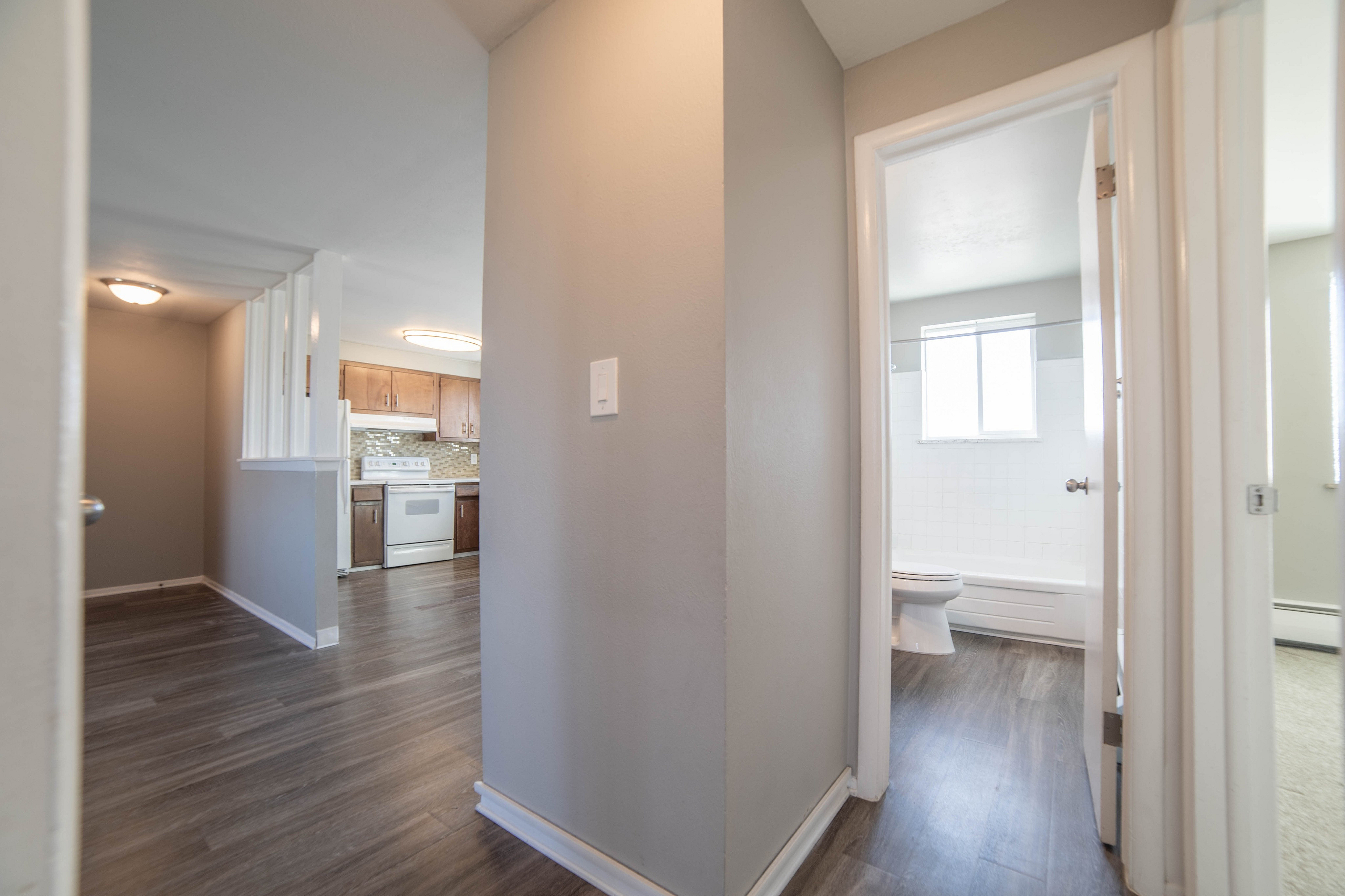 Inviting apartment interior featuring a modern kitchen with wood cabinetry, sleek hardwood floors, and a bright bathroom with natural light.