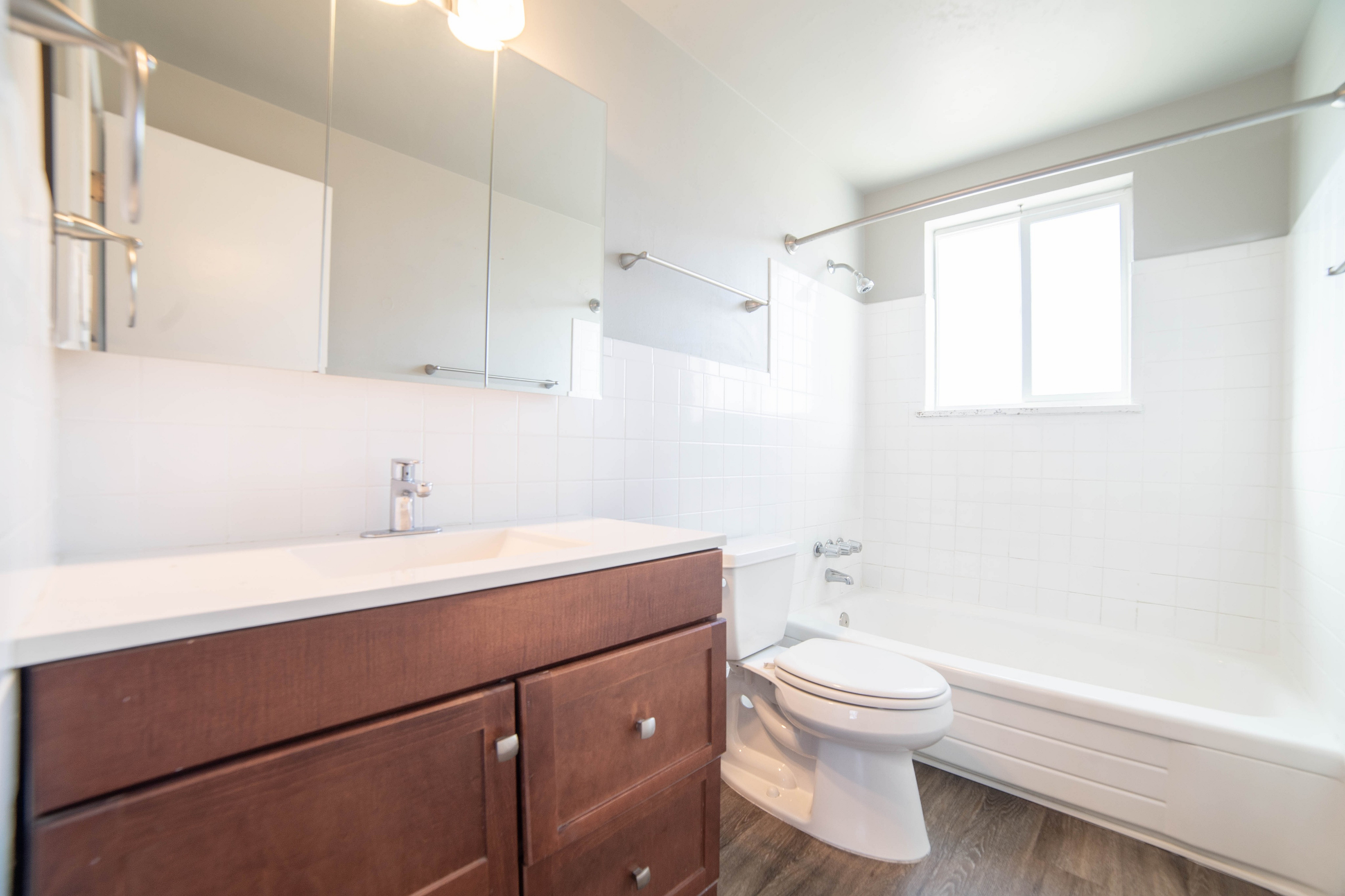 Bright and modern bathroom featuring a sleek wood vanity, pristine bathtub, and elegant tilework.