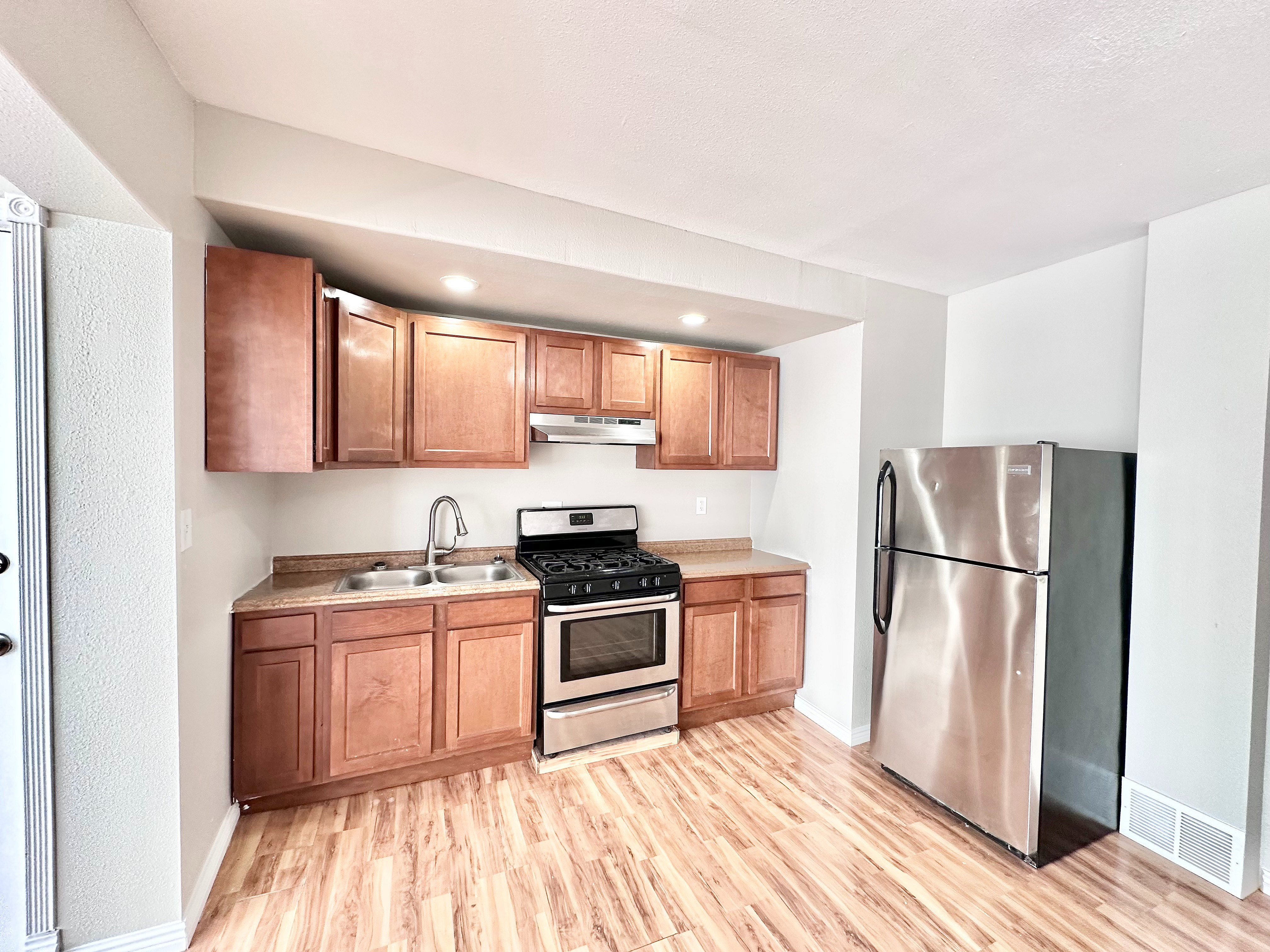Modern kitchen featuring sleek stainless steel appliances, warm wooden cabinetry, and elegant hardwood flooring.