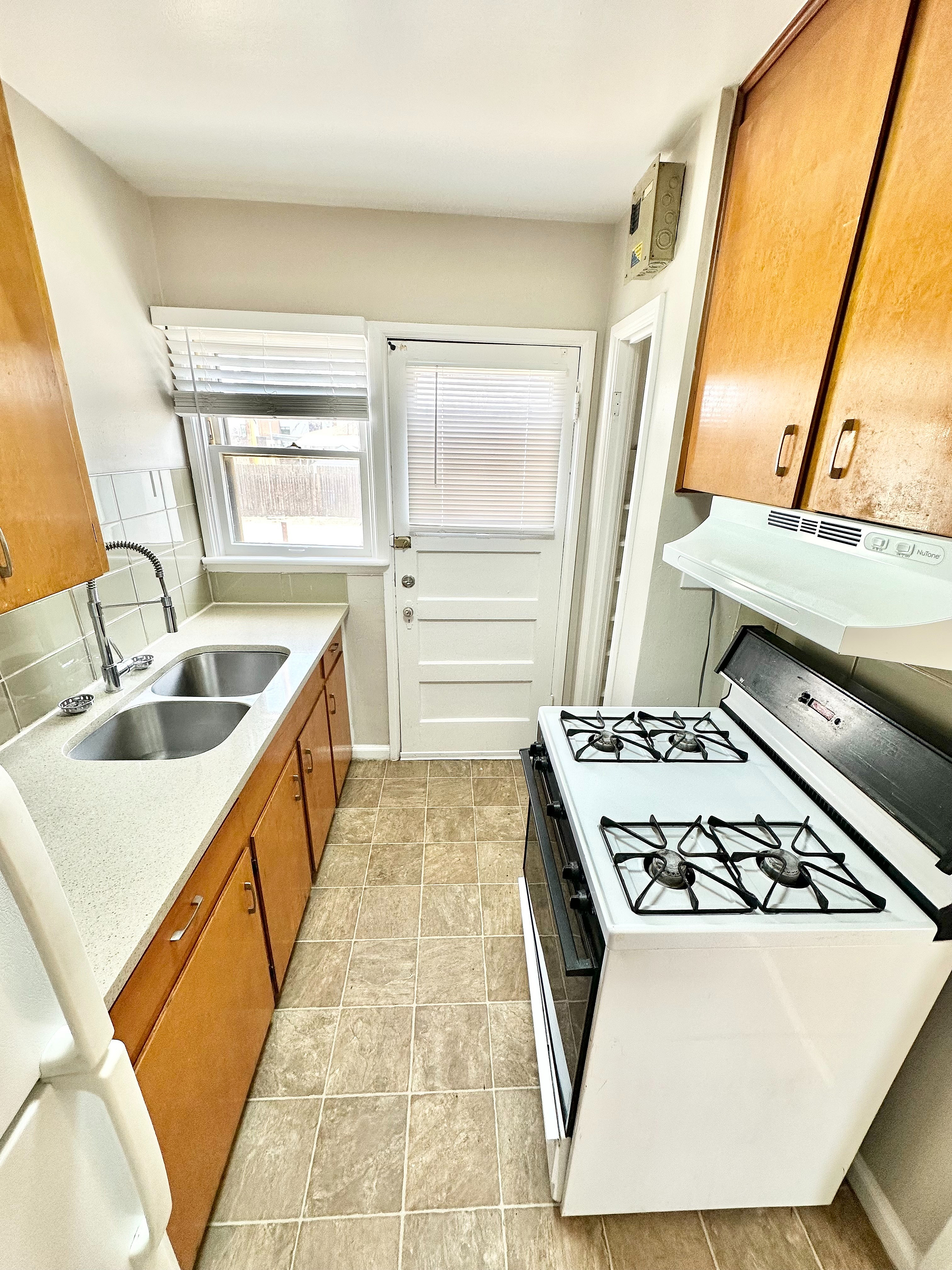 Bright and cozy kitchen featuring modern appliances, sleek countertops, and ample wooden cabinetry for a practical culinary space.