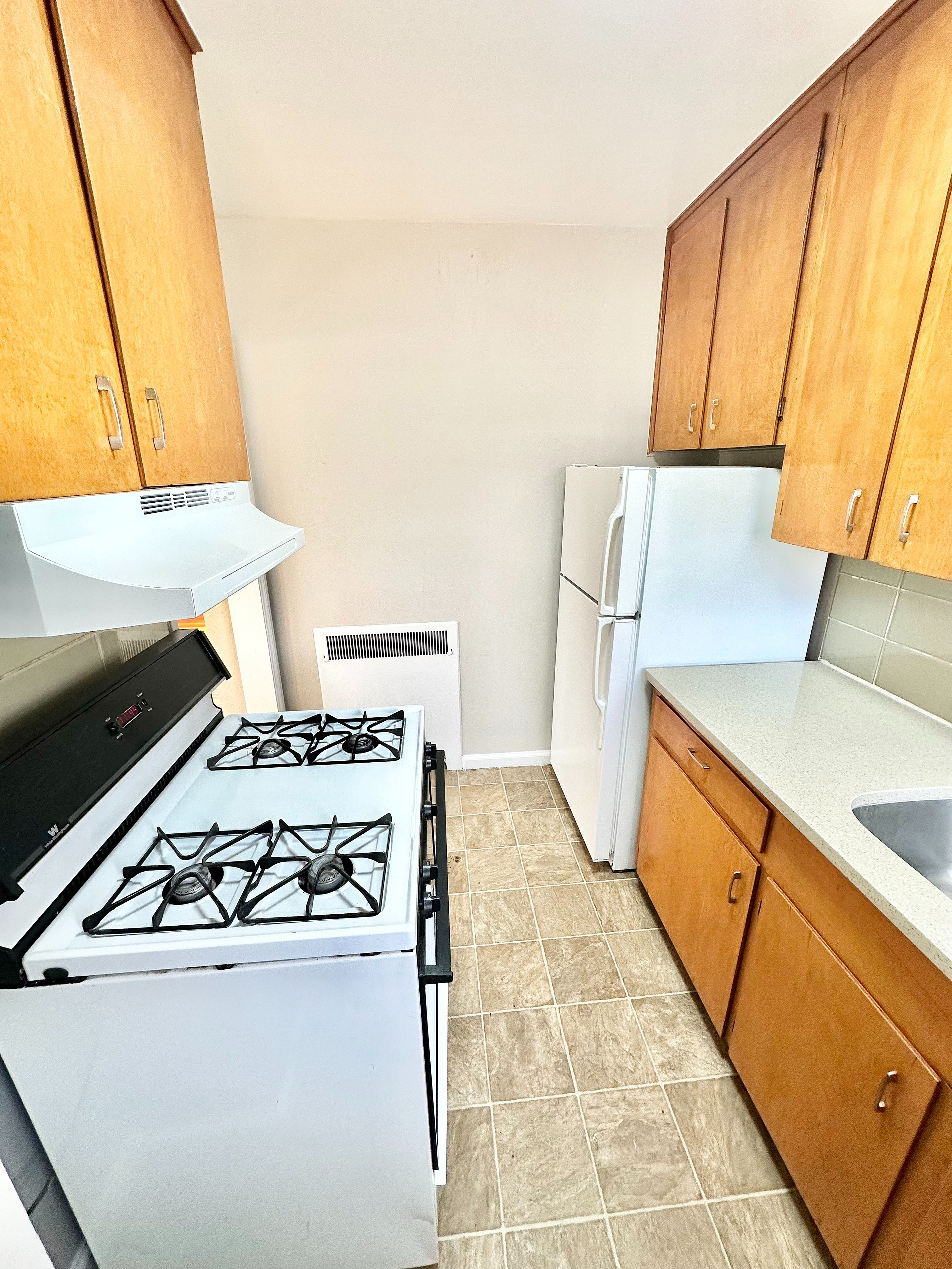 Cozy kitchen with warm wooden cabinets, sleek white appliances, and ample counter space for culinary delights.