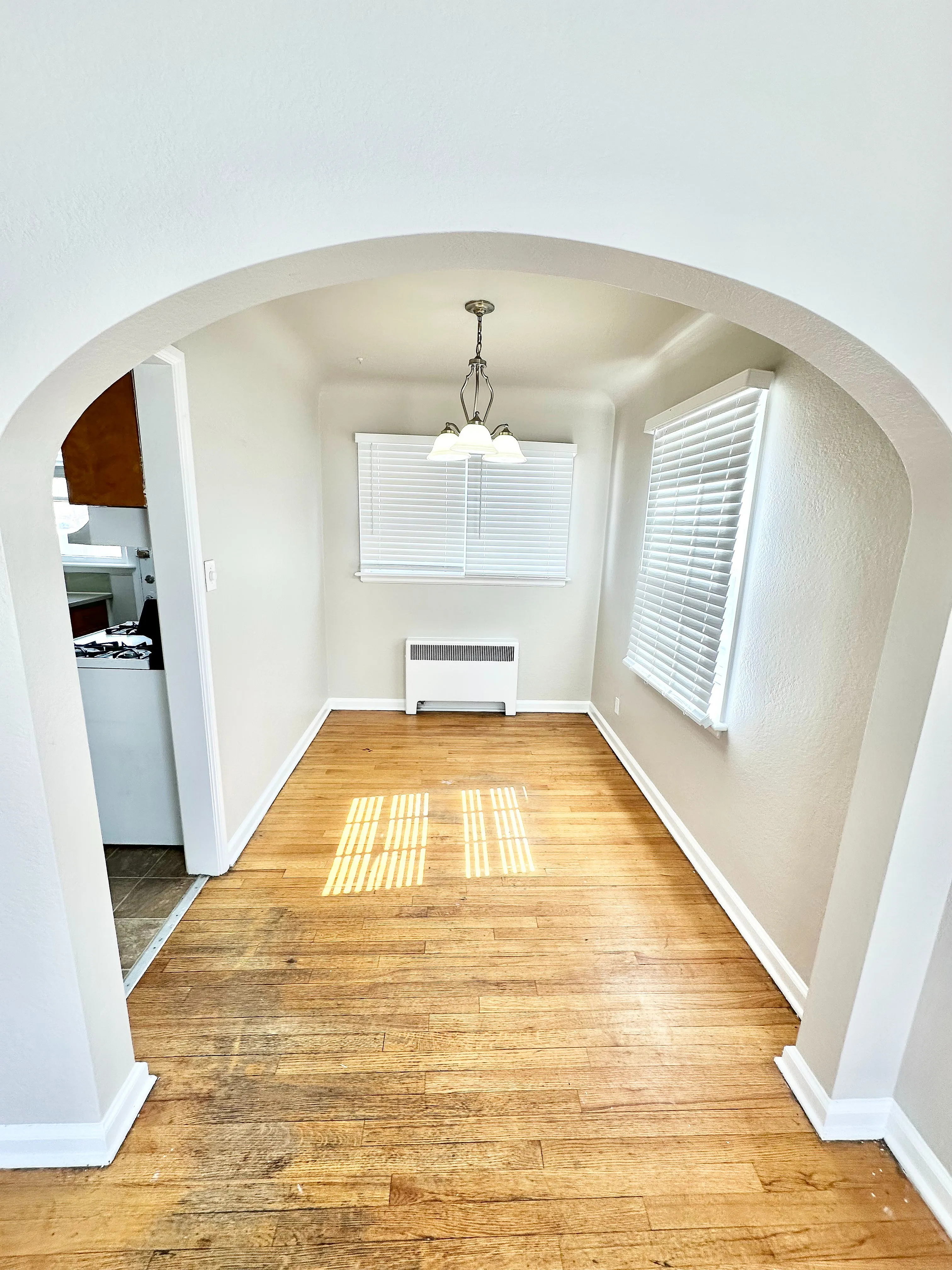 Charming dining area featuring polished hardwood floors, elegant archway, and contemporary lighting.