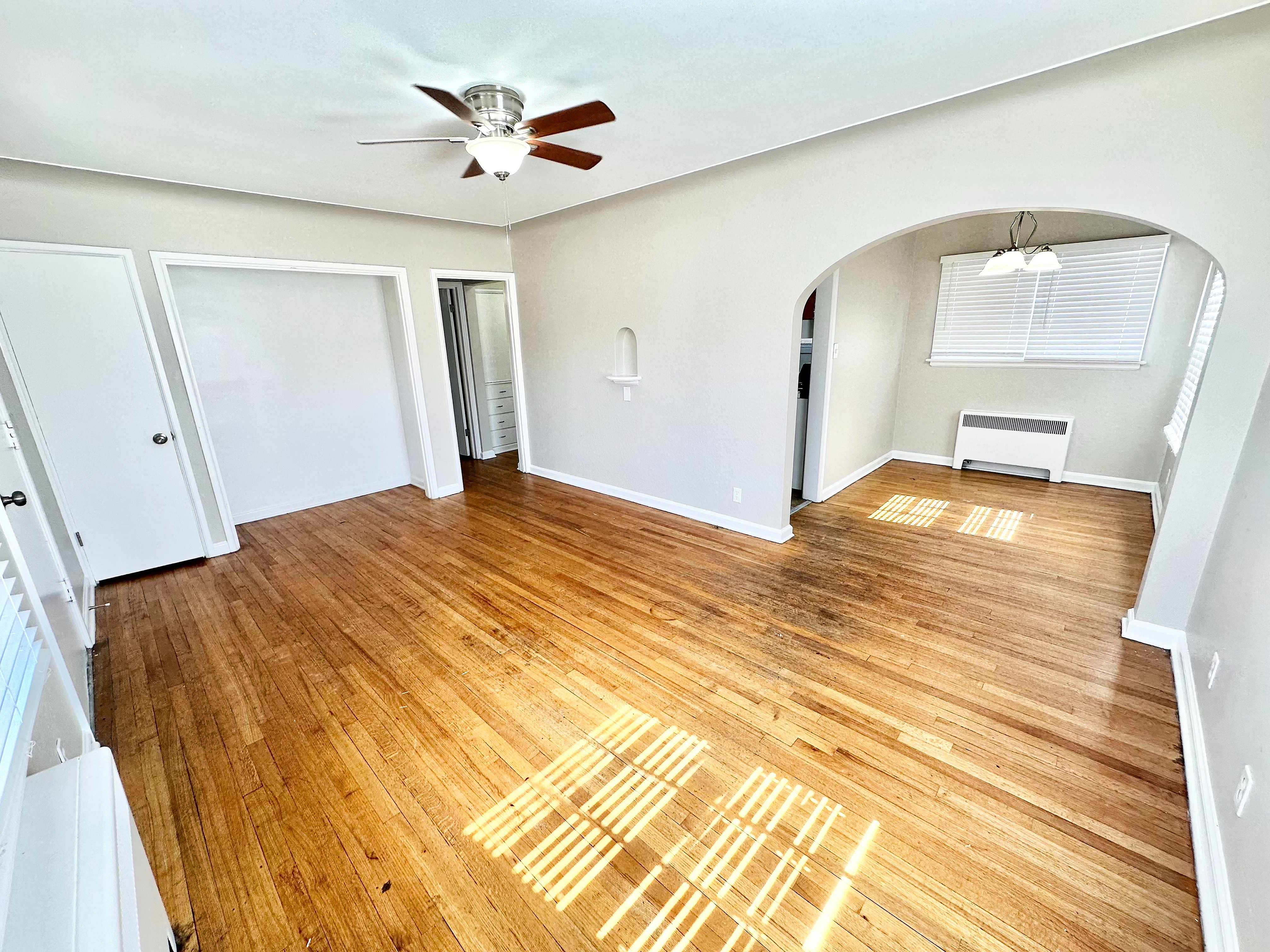 Bright, airy living room with beautiful hardwood floors and a classic arched doorway, perfect for modern living.