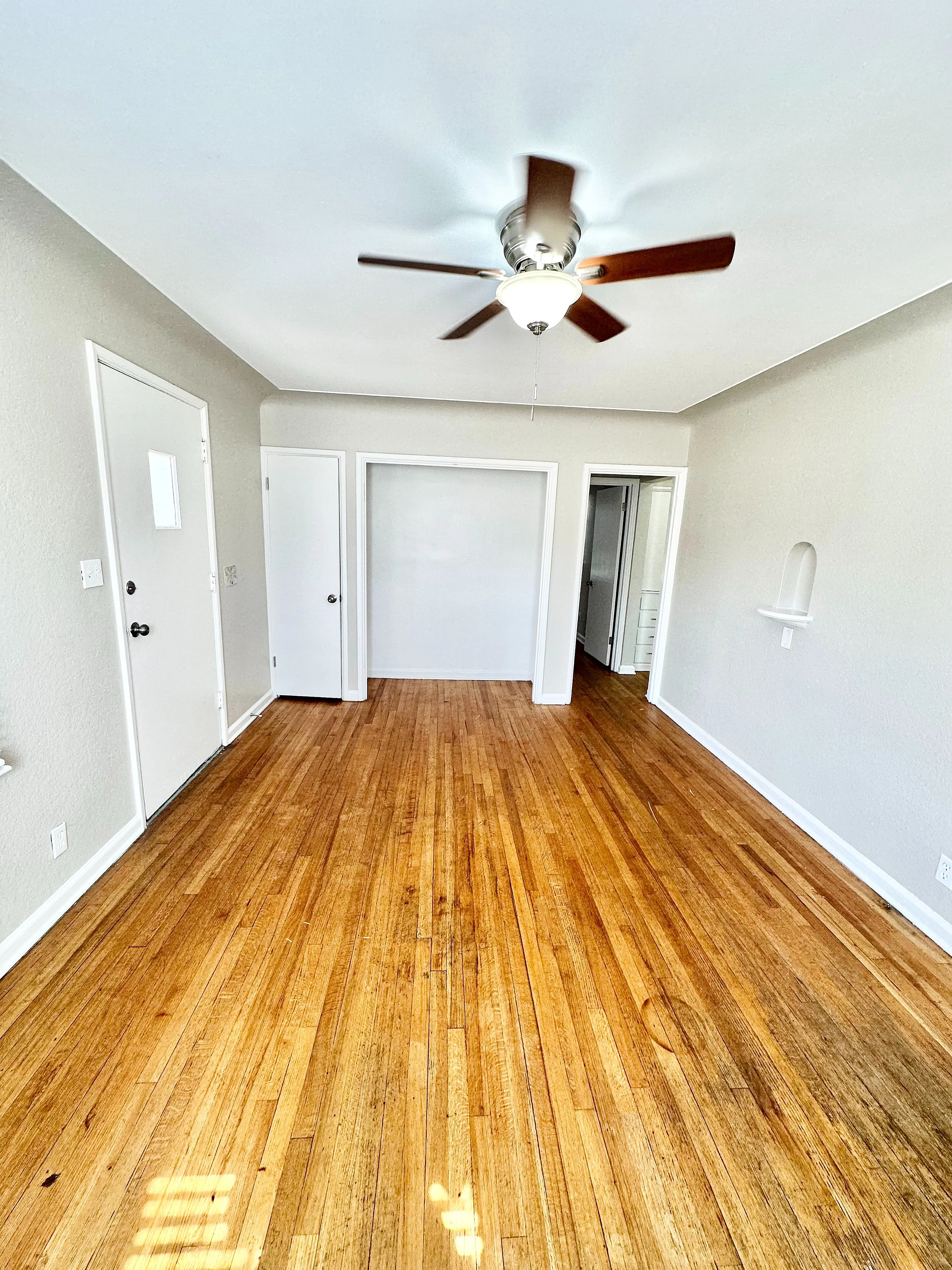 Bright and inviting living space featuring polished hardwood floors and a stylish ceiling fan, perfect for any modern home.
