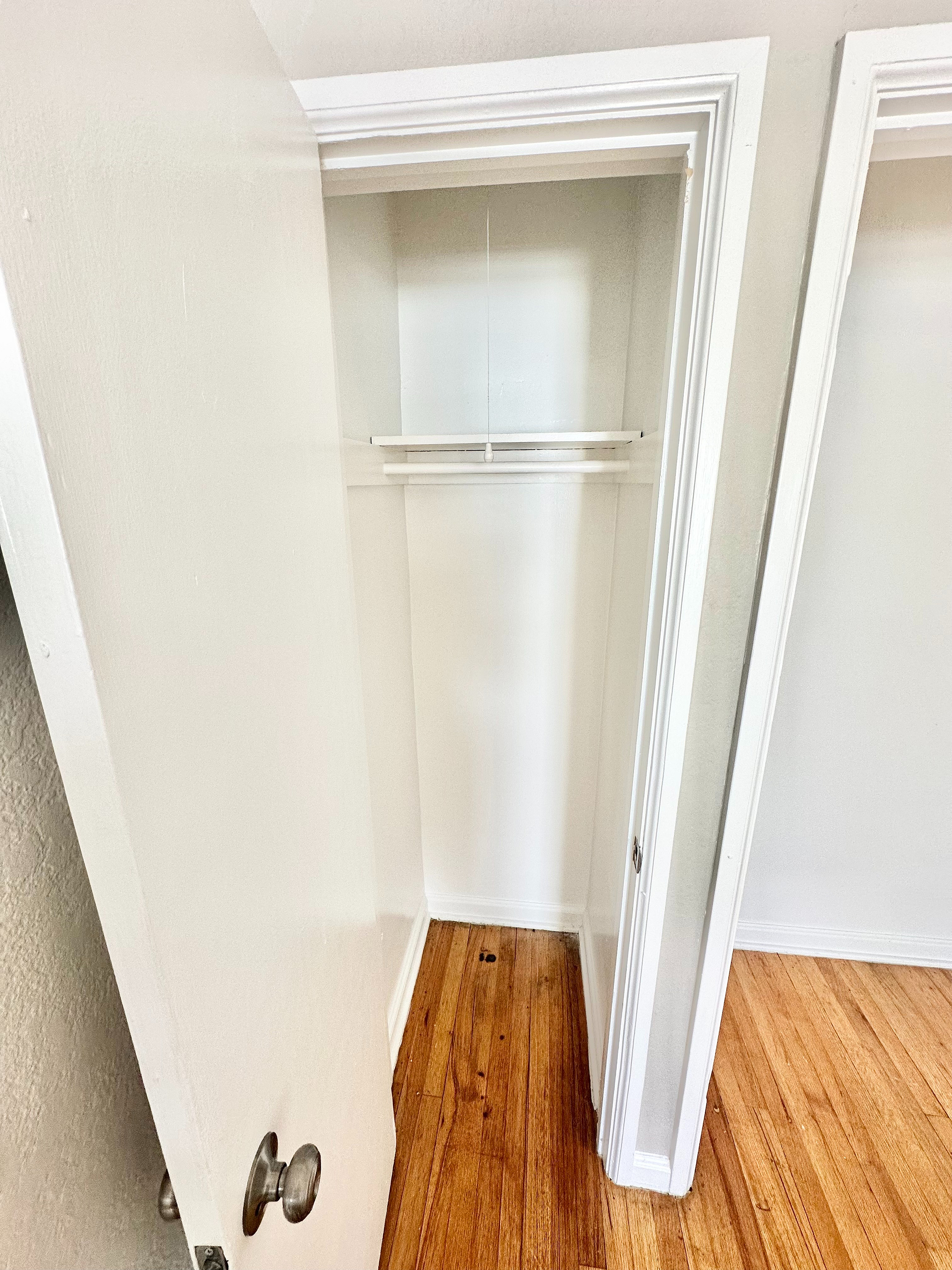 Bright and spacious closet with elegant wooden flooring, highlighting ample storage space in a modern apartment.