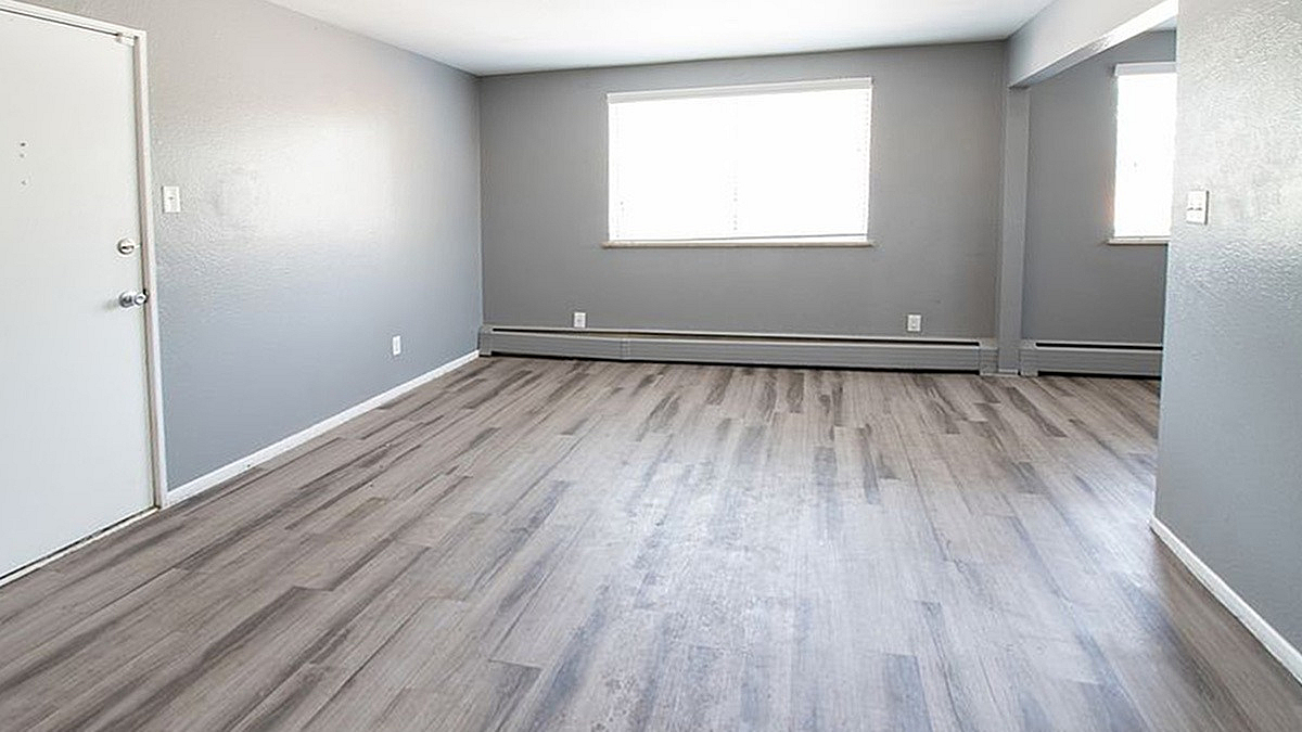 Bright and spacious living area with sleek gray flooring and modern neutral walls, perfect for stylish urban living.