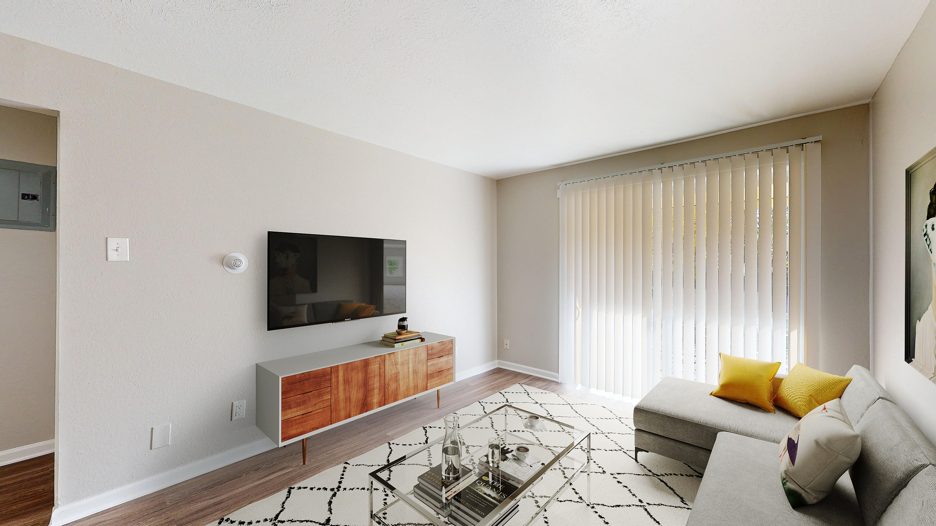 Contemporary living room with a sleek wall-mounted TV, stylish wooden cabinet, and bright natural light from tall vertical blinds.