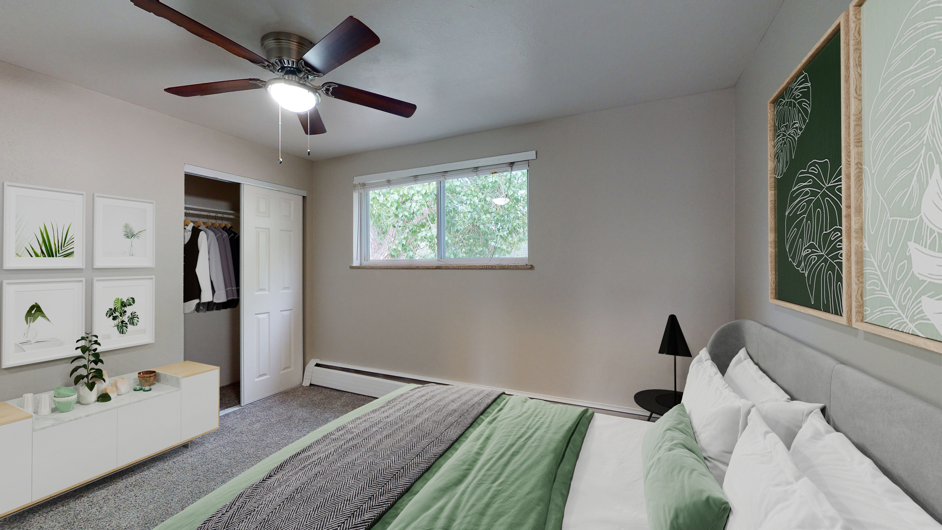 Inviting bedroom with a modern ceiling fan, large window, stylish wall art, and organized closet space with lush tree view.