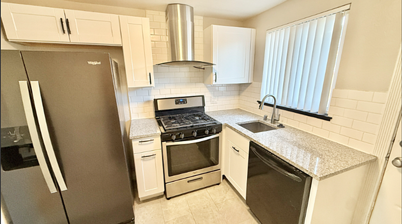 Modern kitchen with sleek stainless steel appliances, white cabinetry, and gleaming granite countertops.