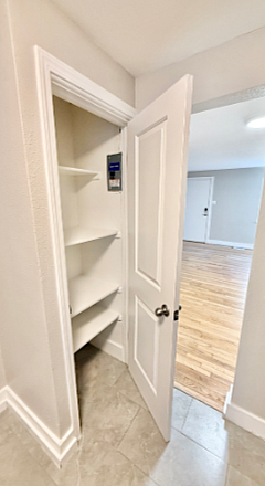 Bright apartment with elegant hardwood floors, open storage closet with multiple shelves, and sleek modern finishes.