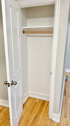 Spacious closet with classic white doors and elegant hardwood flooring, ideal for ample storage.