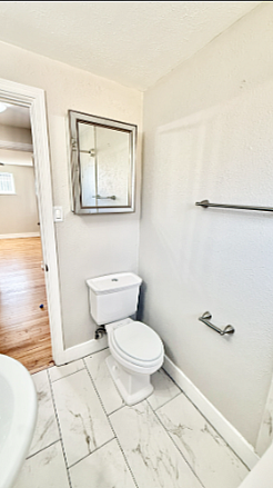 Bright and modern bathroom with elegant tile flooring, a sleek toilet, and a large mirror reflecting natural light.