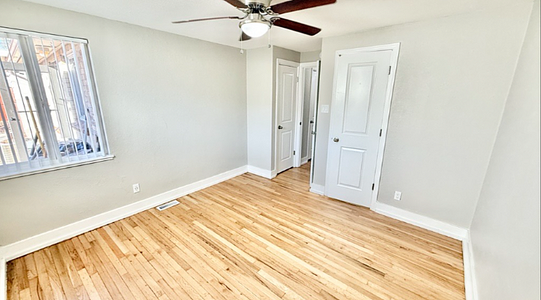 Bright and airy room with elegant hardwood floors, ceiling fan, and ample natural light from a large window.