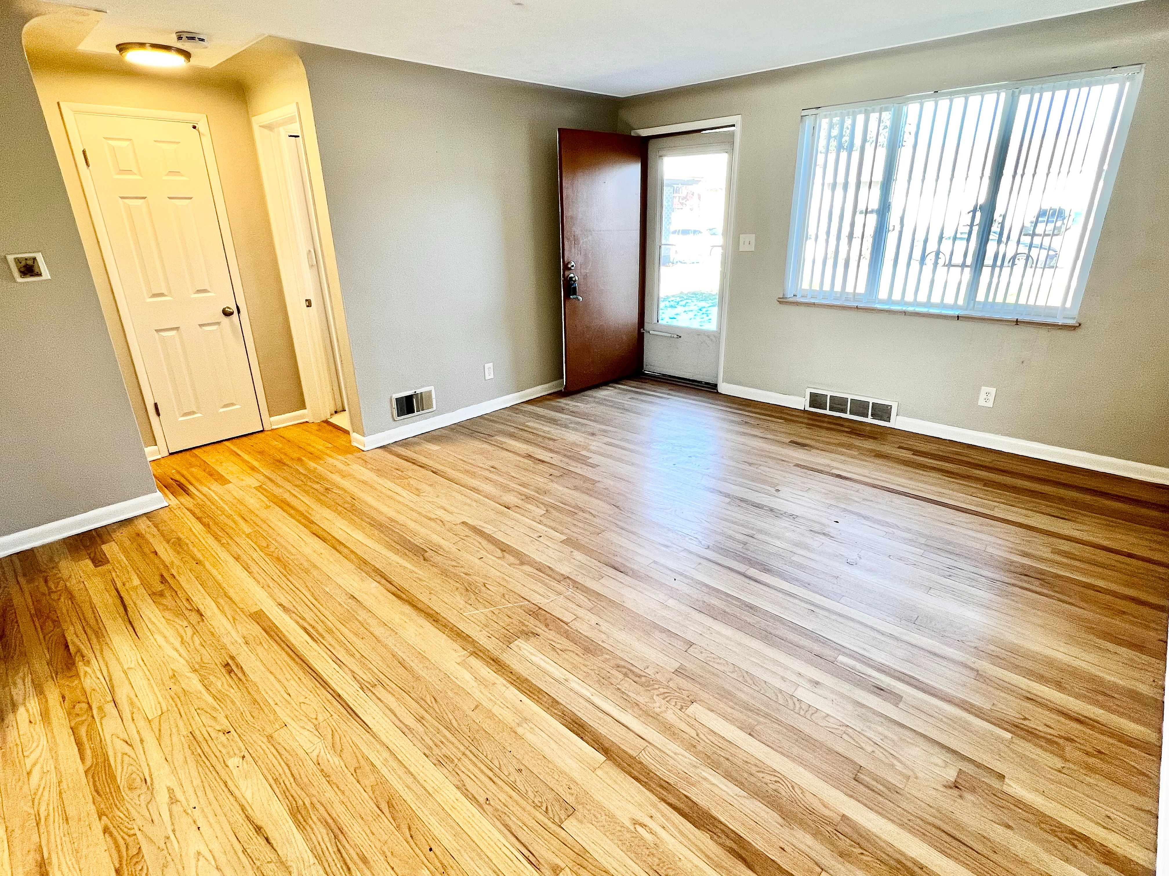 Bright and inviting living room with elegant hardwood floors, large window, and modern door creating a warm, welcoming atmosphere.