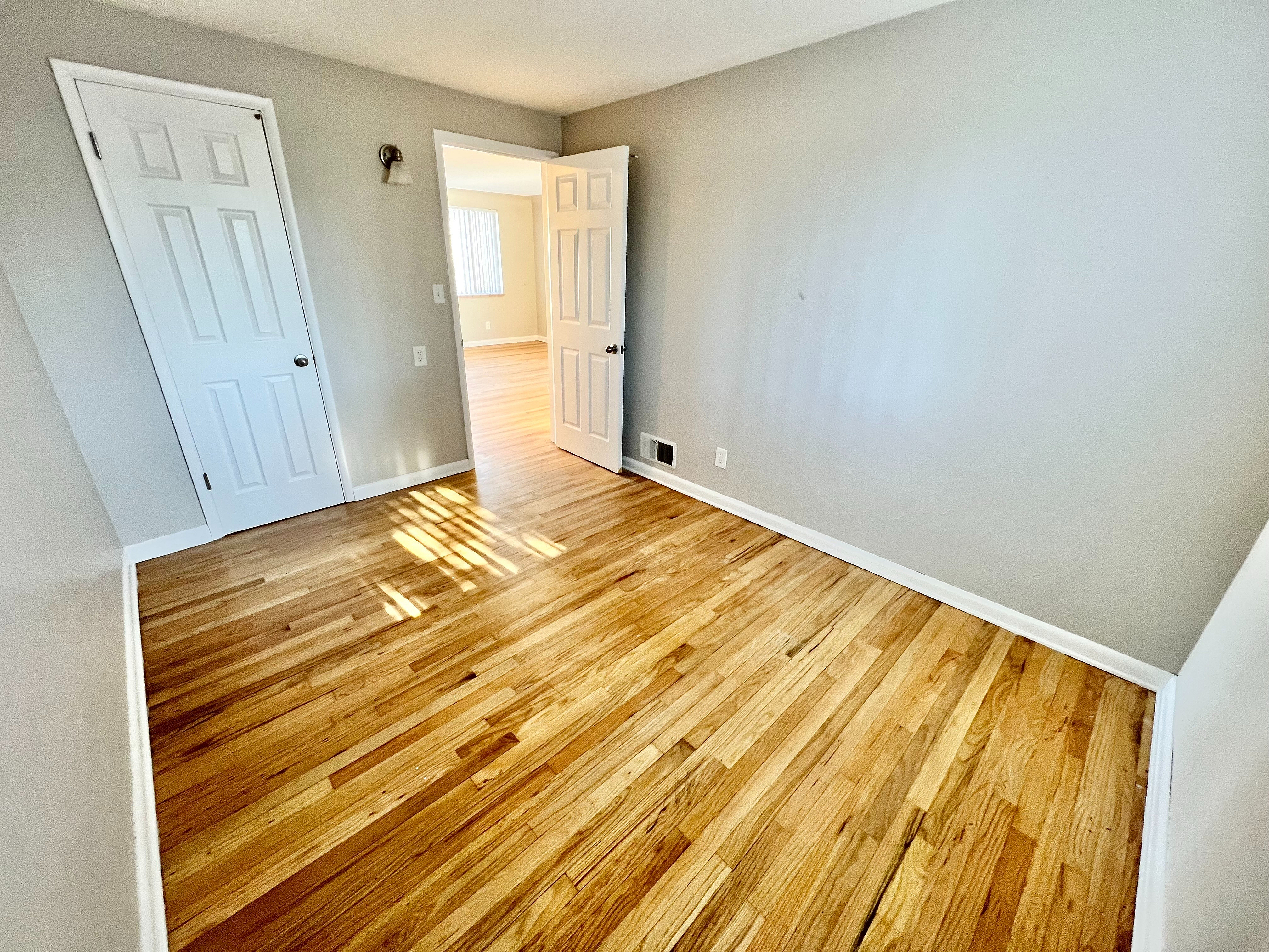 Bright and welcoming room with elegant wooden floors, large doors, and ample natural light.