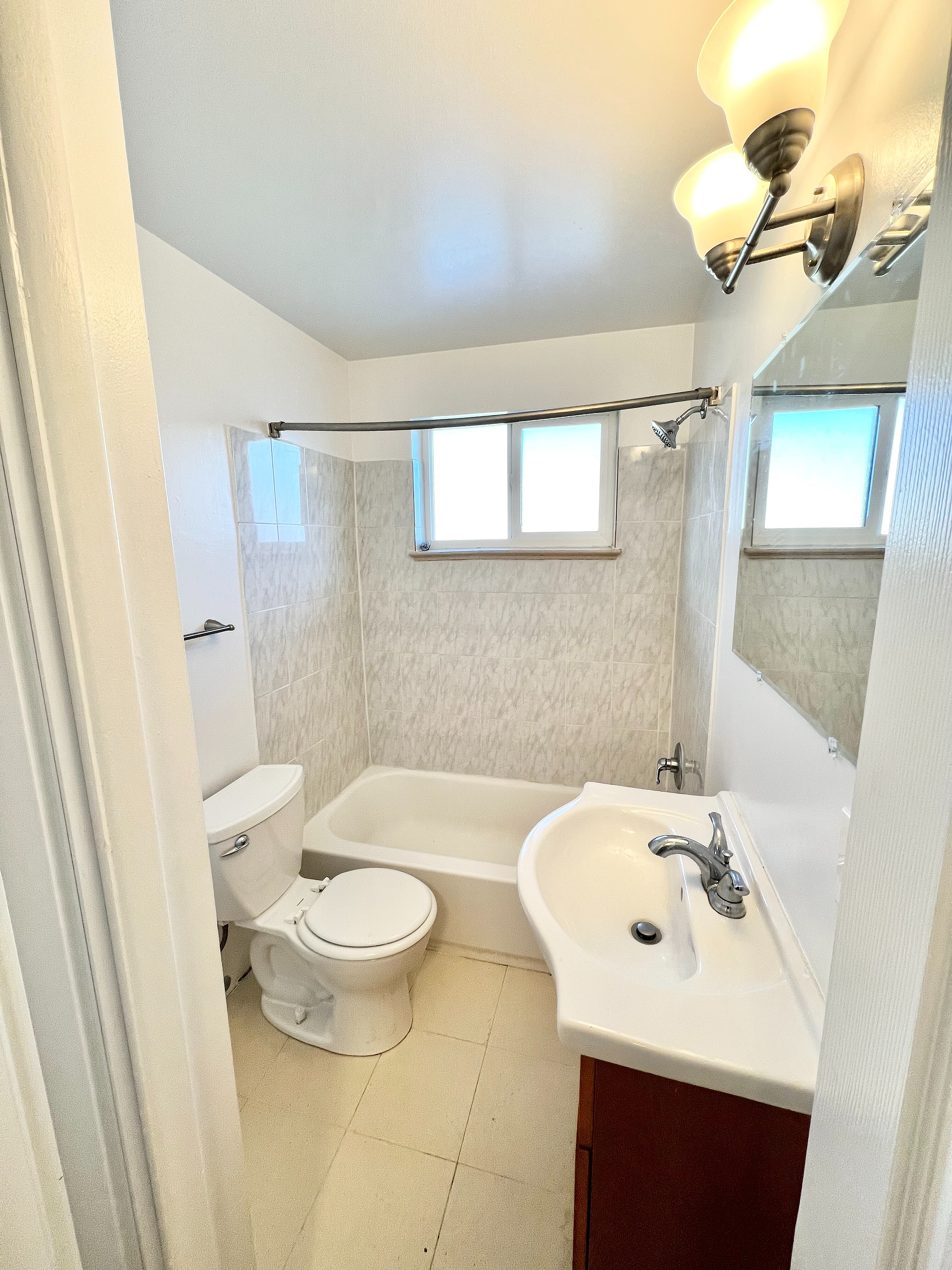 Bright and inviting bathroom with modern fixtures, featuring a classic tub-shower combo and elegant lighting.