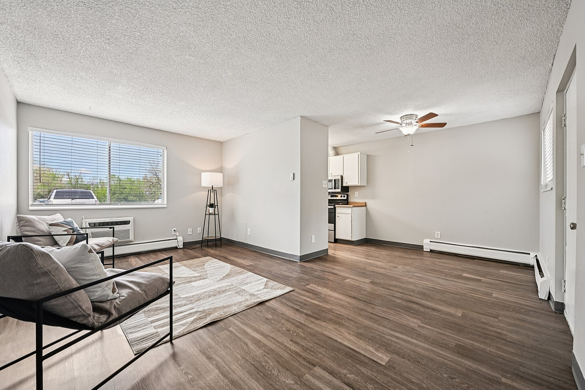 Bright and airy living room with modern seating, wooden flooring, and a cozy atmosphere adjacent to a compact kitchen.