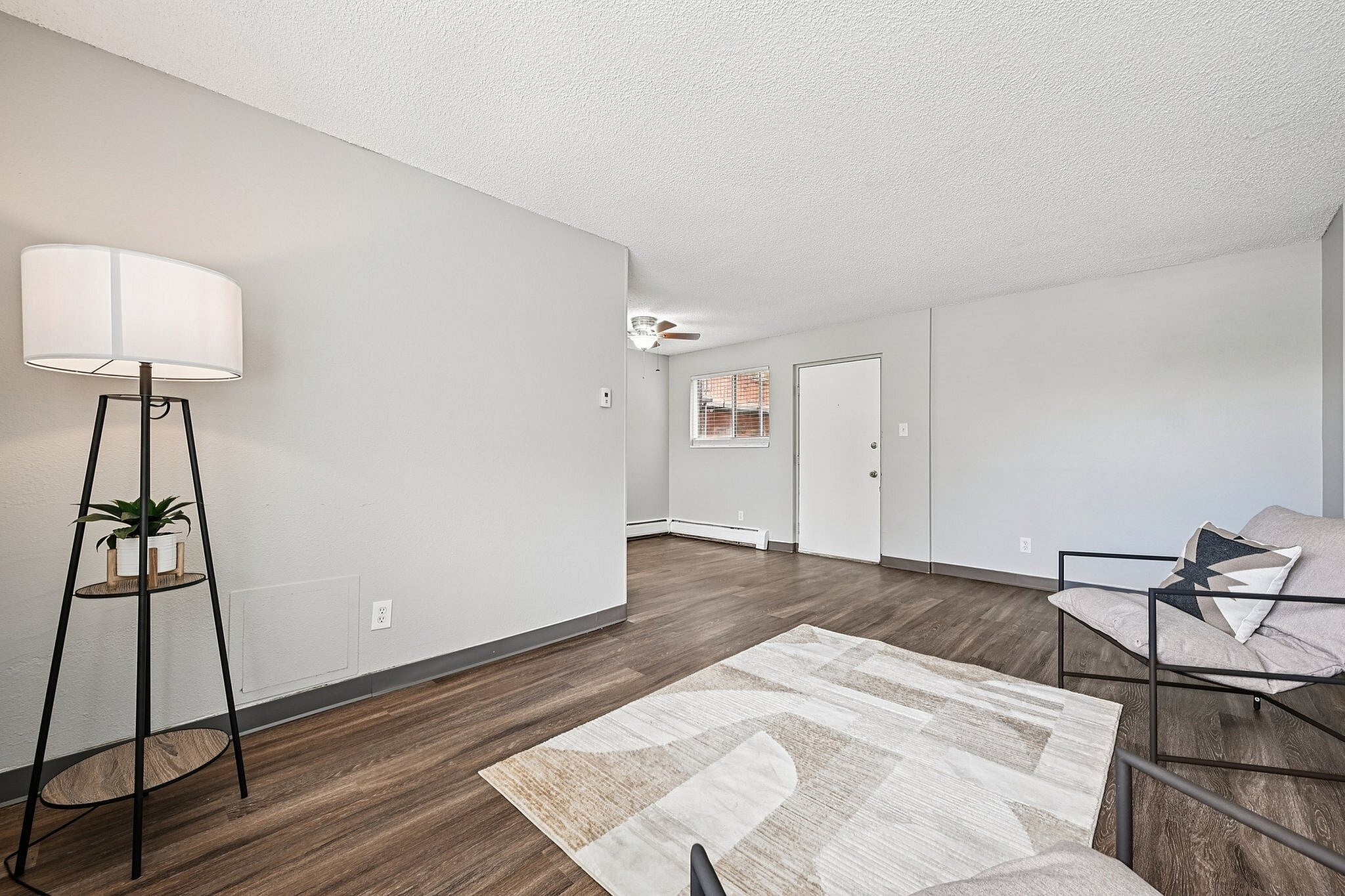 Bright and inviting living room with modern decor, featuring a stylish floor lamp, cozy seating area, and elegant wood flooring.