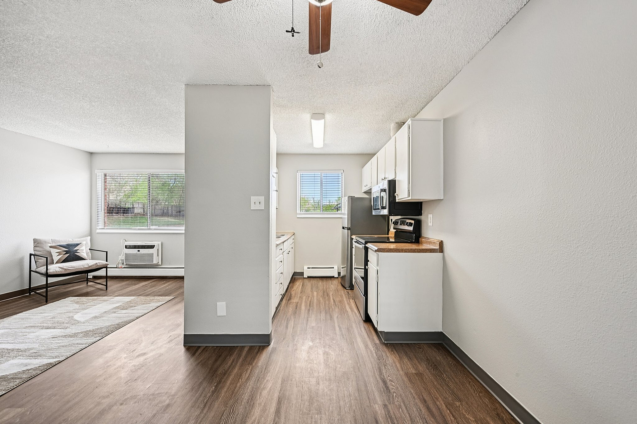 Open and airy apartment interior featuring a modern kitchen with stainless steel appliances, bright living area, and elegant wood flooring.