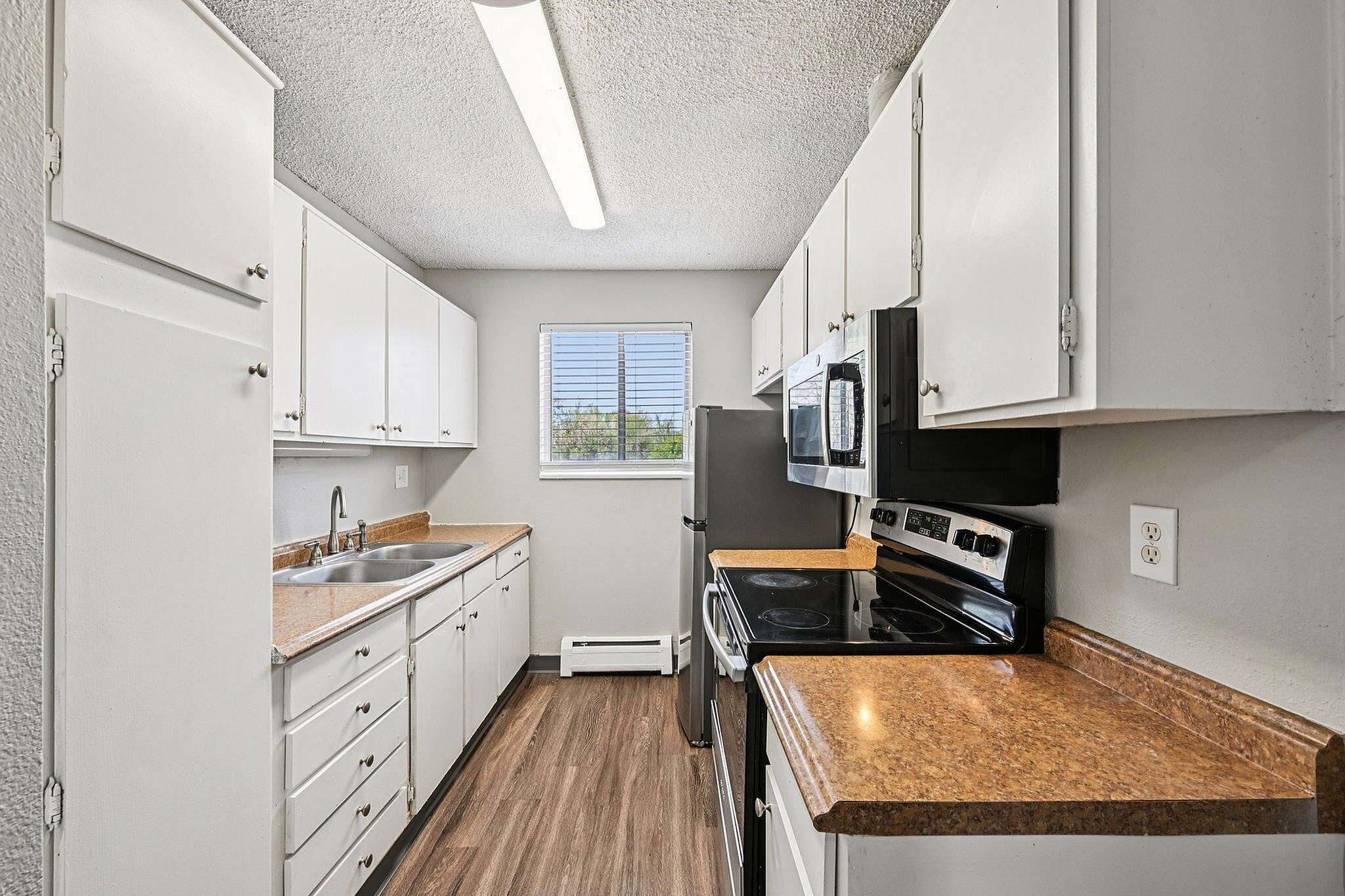 Bright and modern galley kitchen with sleek countertops, ample white cabinetry, and stainless steel appliances enhanced by natural light.