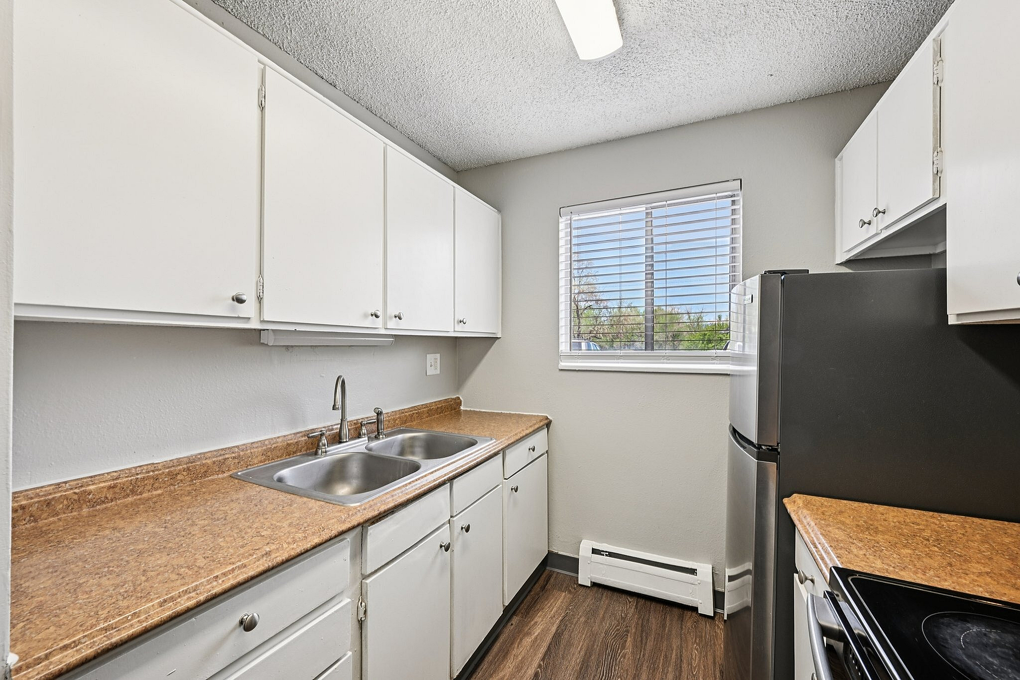 Modern kitchen with sleek stainless steel appliances, elegant wooden countertops, and ample cabinet storage complemented by bright natural light through the window.