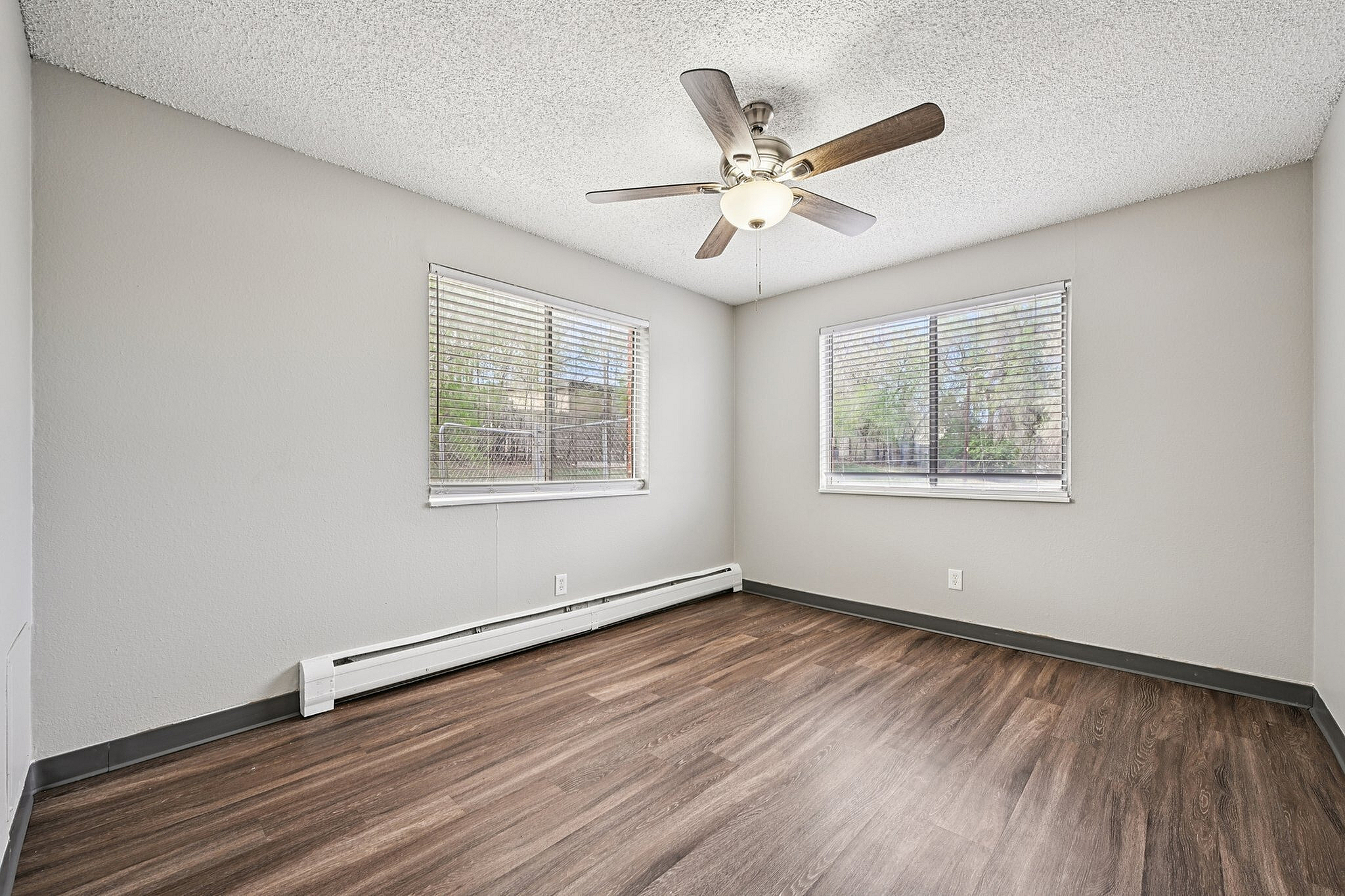 Bright and airy bedroom with modern ceiling fan, large windows, and elegant wood flooring.
