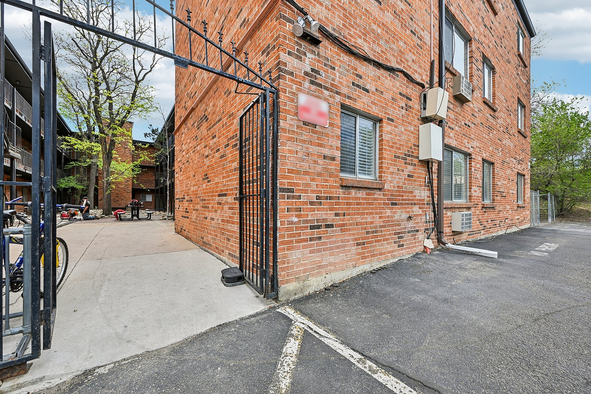 Charming brick apartment exterior with gated entrance and a serene courtyard view.