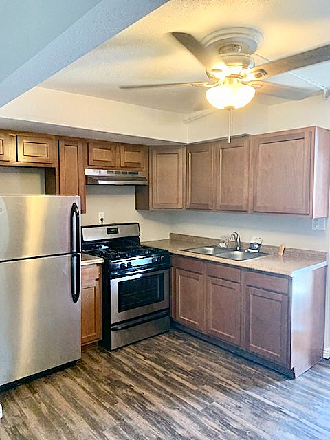 Charming kitchen with modern stainless steel appliances, rich wood cabinetry, and elegant wood flooring.
