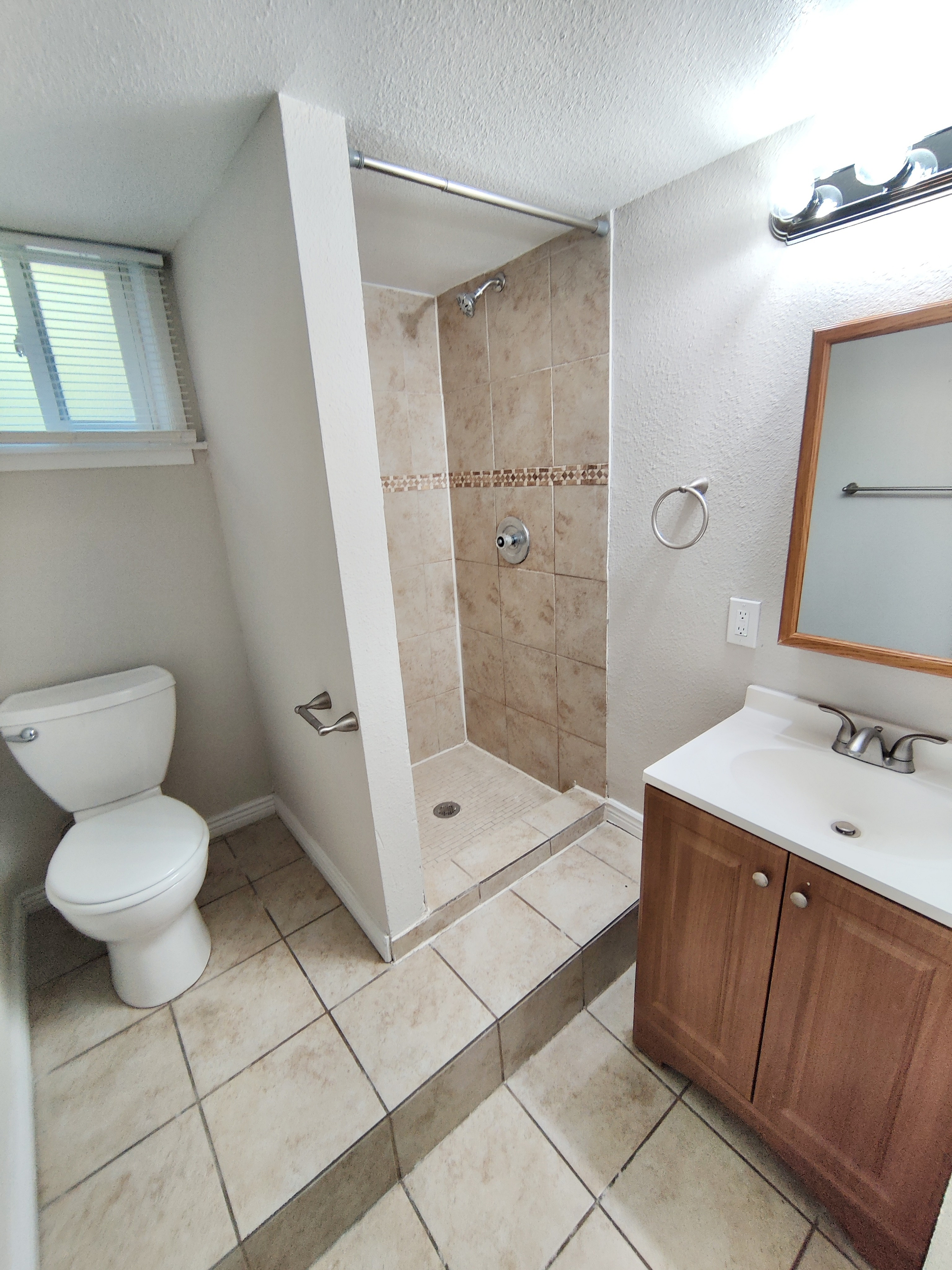 Bright and modern bathroom featuring a sleek tiled shower, elegant vanity, and efficient layout.