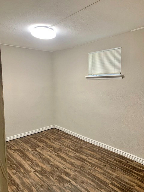 Cozy apartment room with elegant wood flooring and soft neutral walls, illuminated by modern lighting.