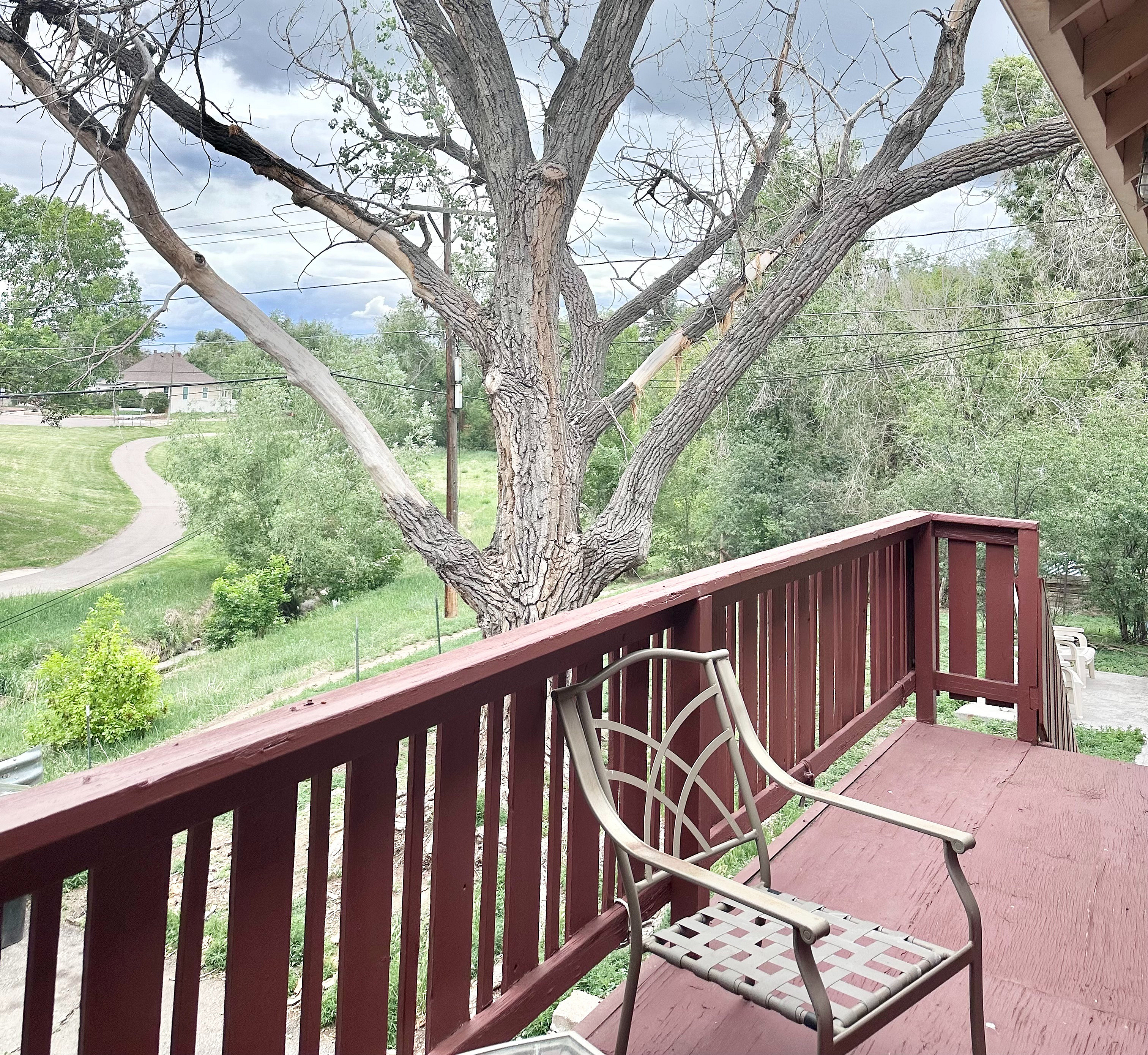 Charming balcony view with a tranquil backdrop of lush greenery and a scenic pathway, perfect for relaxation.