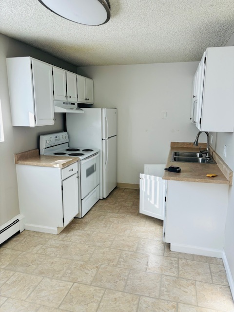 Compact white kitchen with modern appliances and ample counter space.