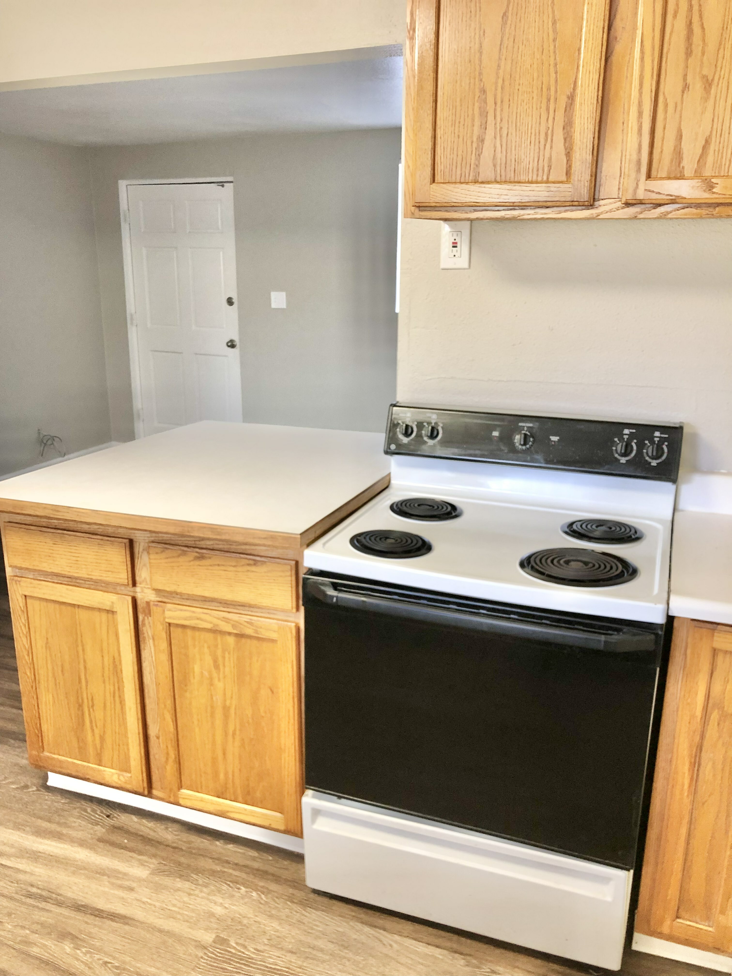 Inviting kitchen space featuring a classic electric stove, warm wooden cabinets, and sleek white countertops, perfect for culinary enthusiasts.