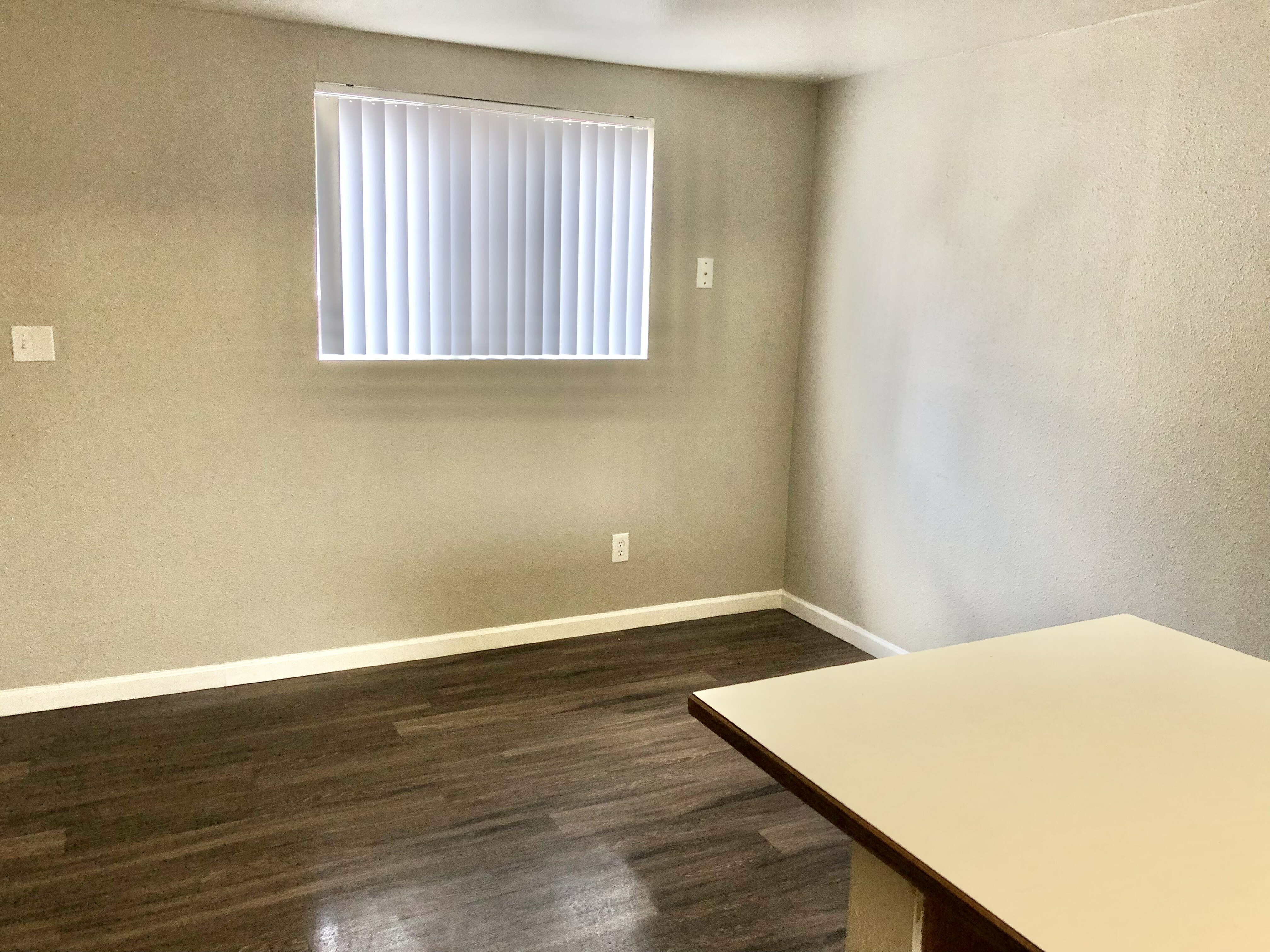 Bright room with modern wood flooring and a large window for natural light, perfect for a cozy living or dining area.