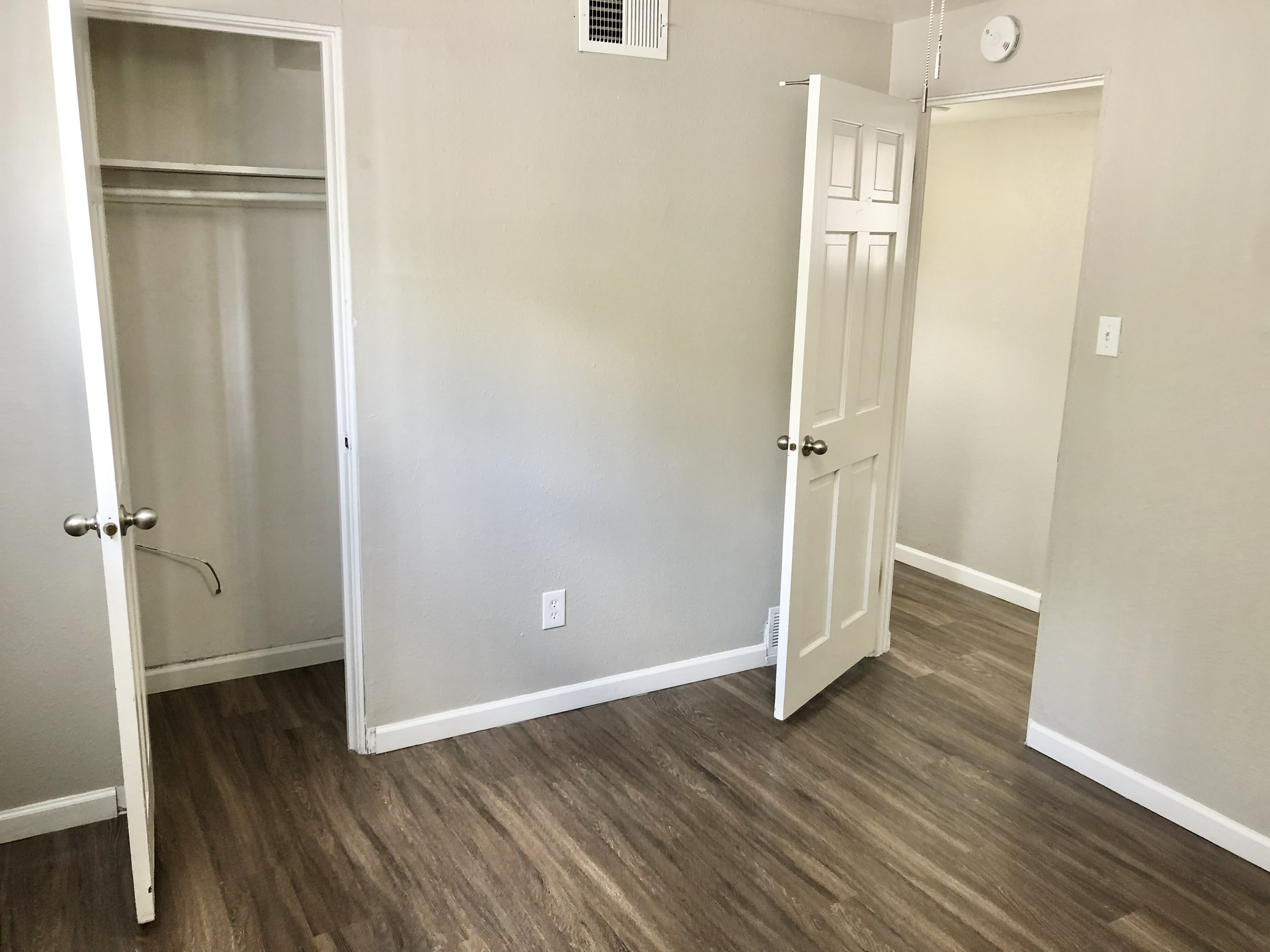 Bright, modern room showcasing stunning hardwood floors and an inviting open closet, perfect for a cozy living space.