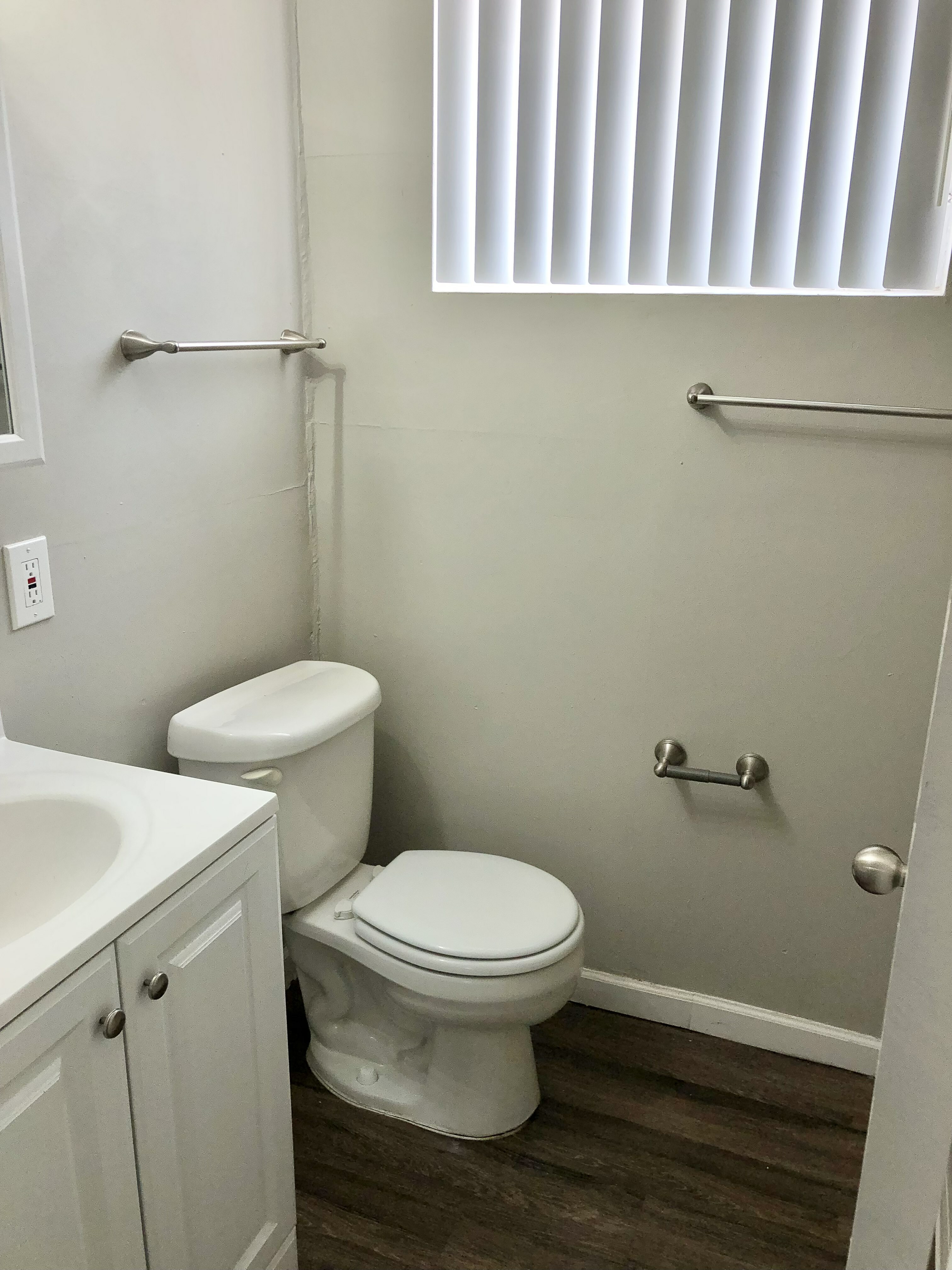 Bright and modern bathroom with sleek fixtures, white cabinetry, and elegant window blinds.