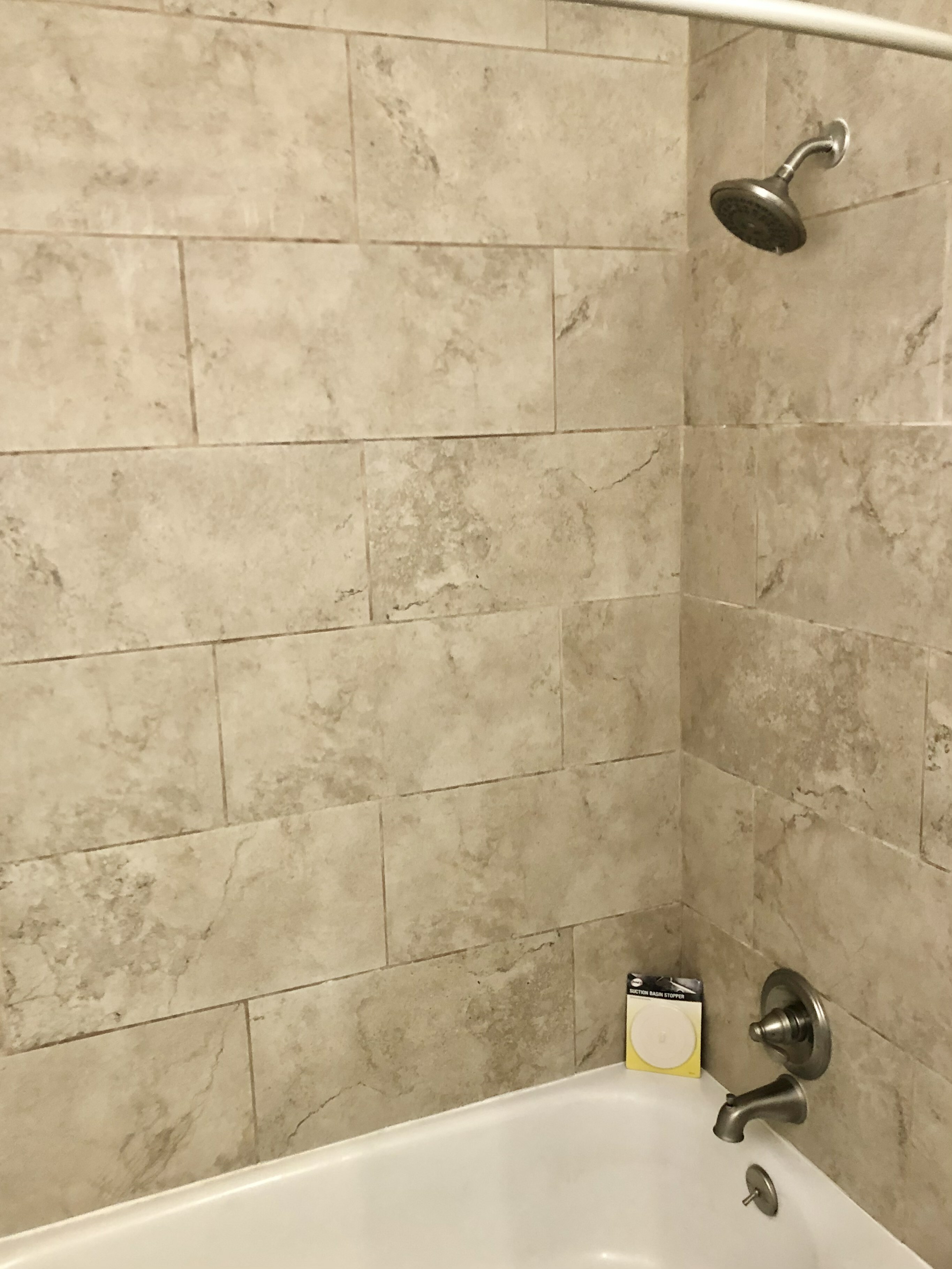 Modern bathroom with elegant stone tile walls, sleek chrome fixtures, and a clean bathtub perfect for relaxation.
