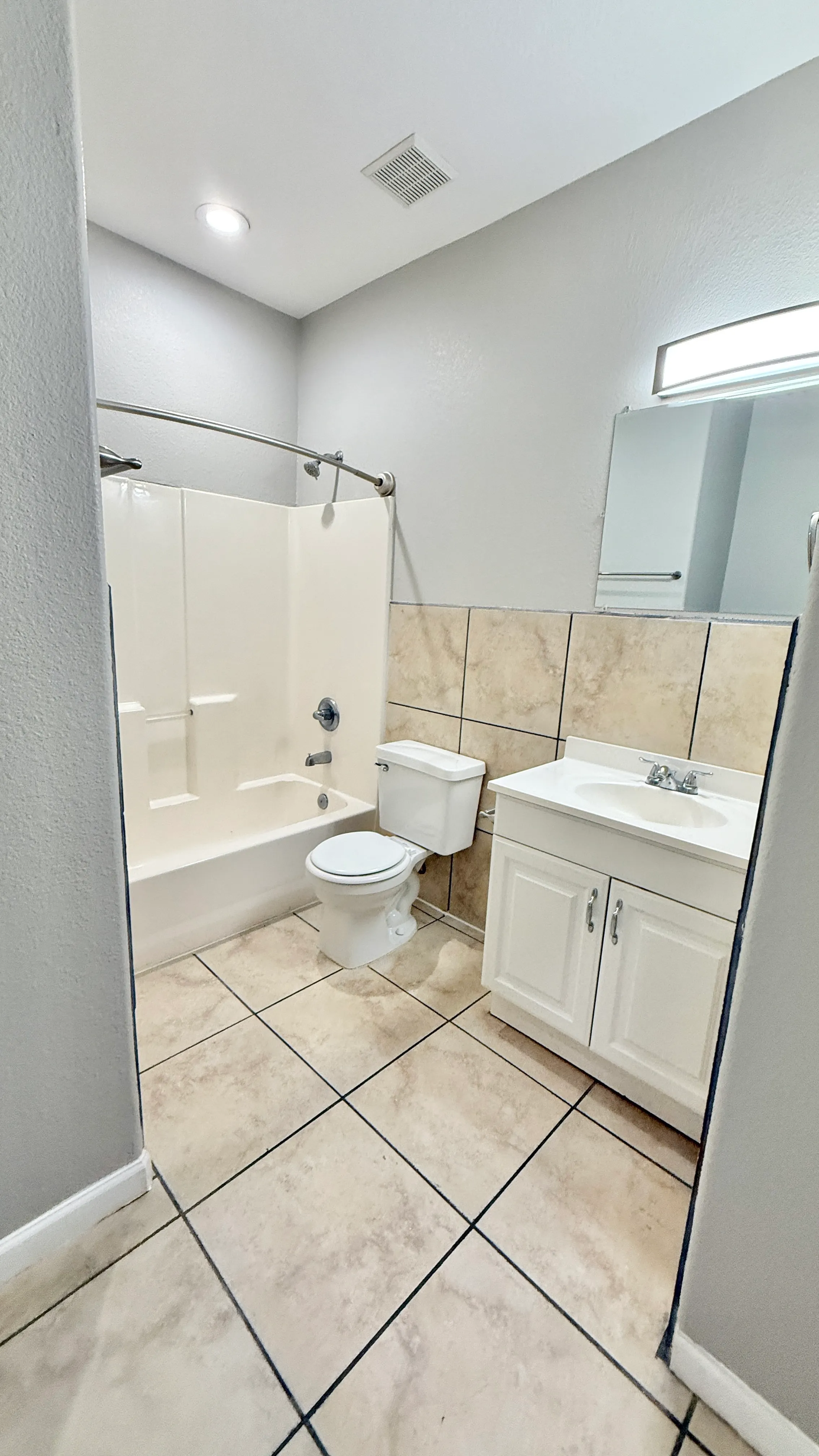 Modern bathroom featuring elegant tile flooring, a sleek vanity with ample storage, and a pristine shower-tub combination.