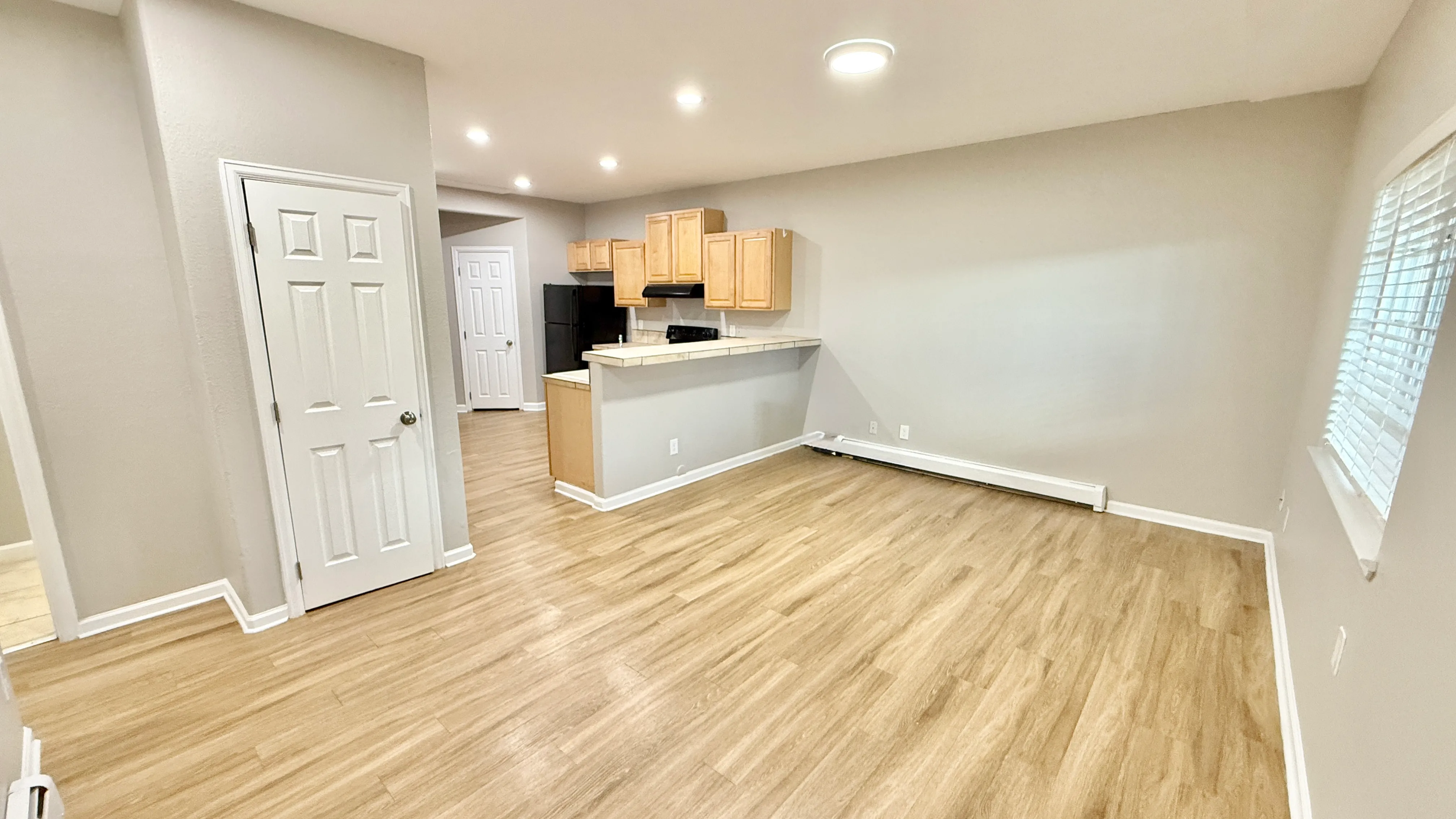 Inviting open-plan living and kitchen area with modern wooden flooring, ample natural light, and sleek cabinetry.