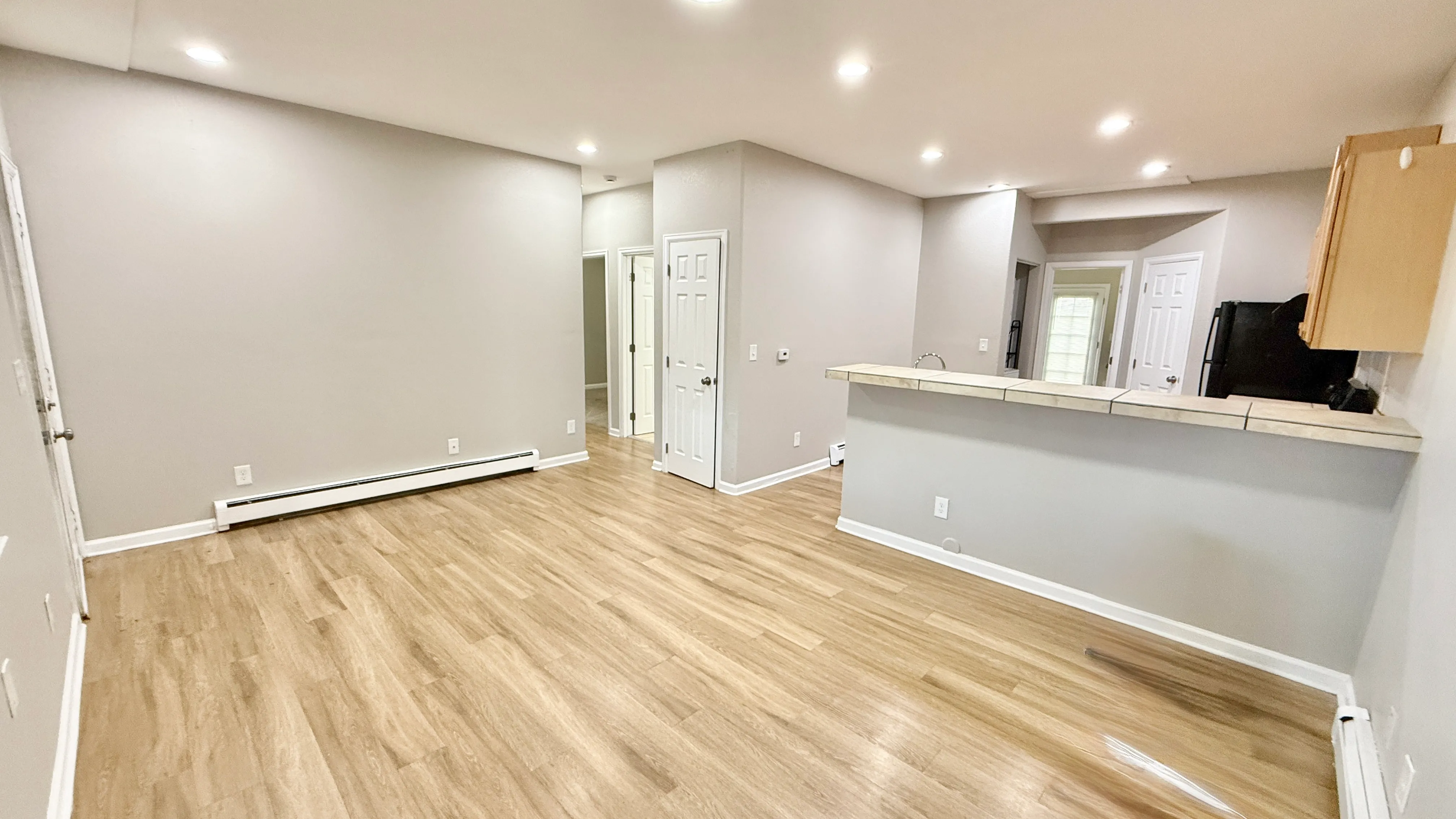 Bright and inviting open-concept living space with sleek hardwood floors, modern lighting, and a functional kitchen counter.