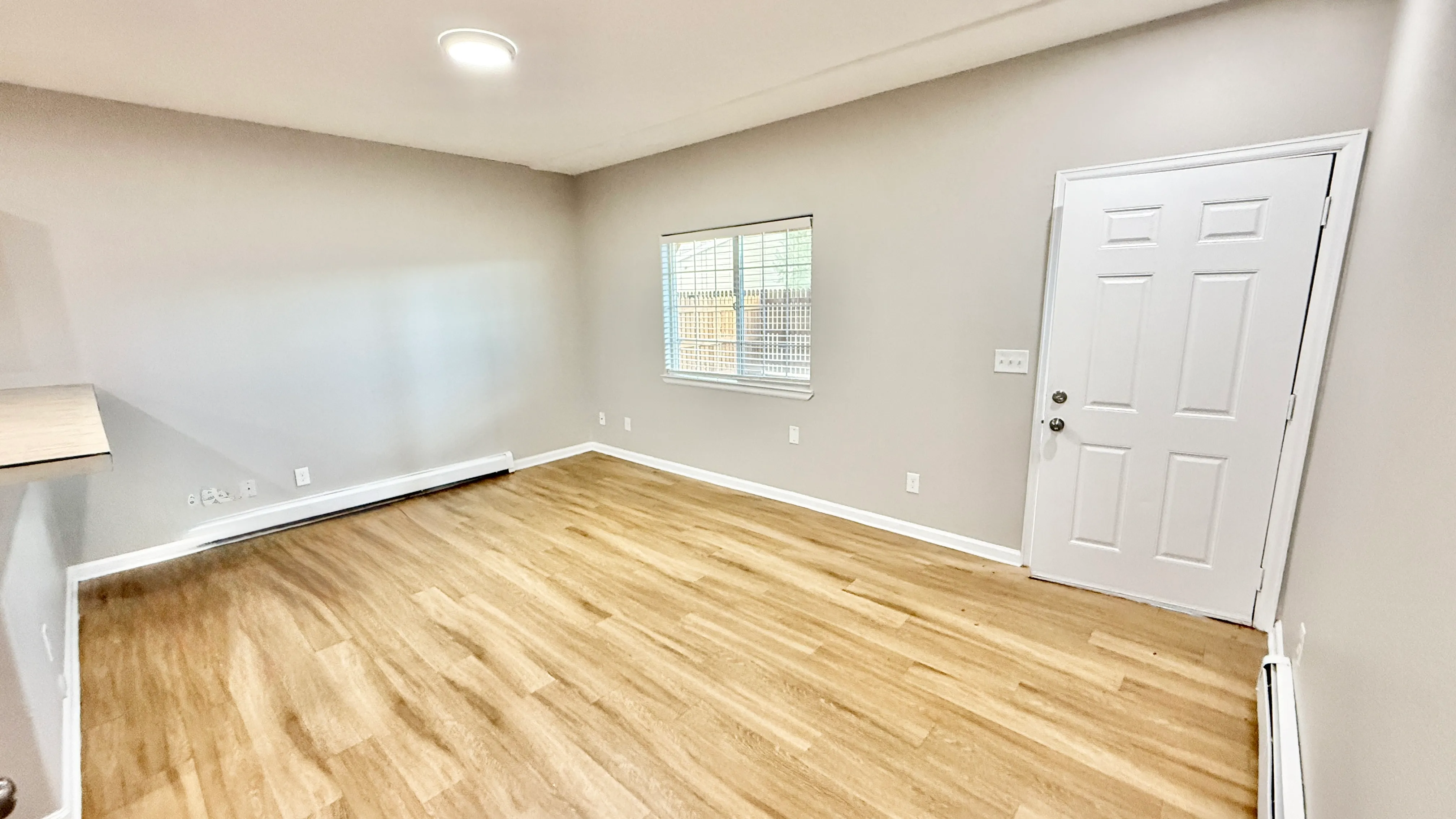 Bright and inviting living space featuring modern hardwood flooring, neutral walls, and abundant natural light from a large window.