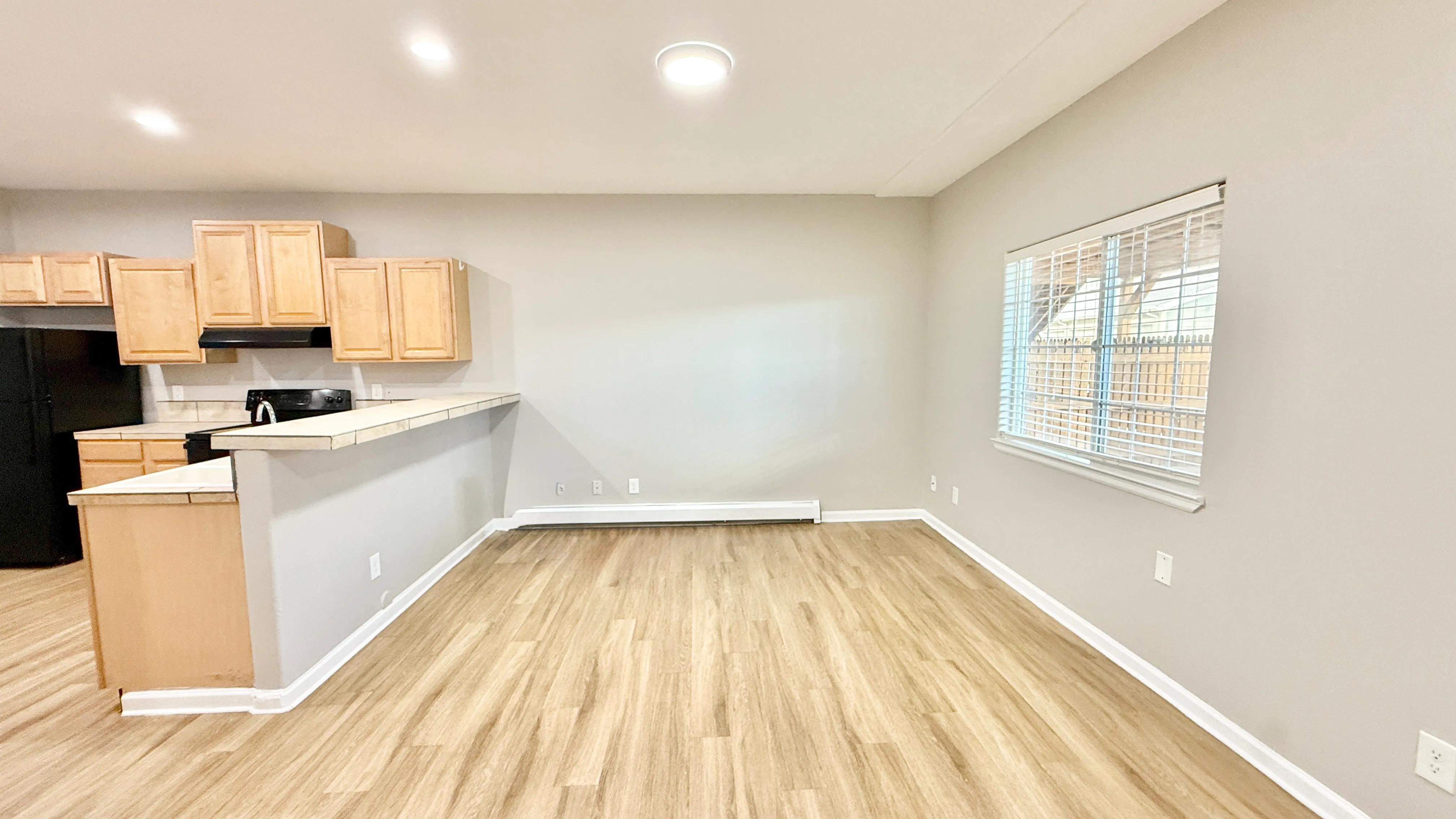 Inviting open-plan living and kitchen space with natural wood cabinetry and elegant flooring, enhancing the bright and airy ambiance.