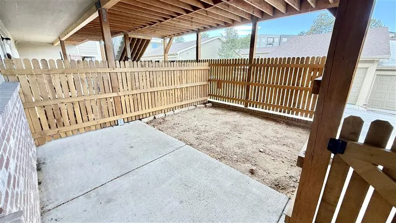Charming fenced patio area with covered wooden ceiling, perfect for outdoor relaxation and privacy.