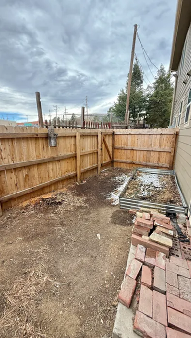 Cozy backyard space with a wooden privacy fence, ideal for gardening or outdoor relaxation, complemented by rustic brick details.