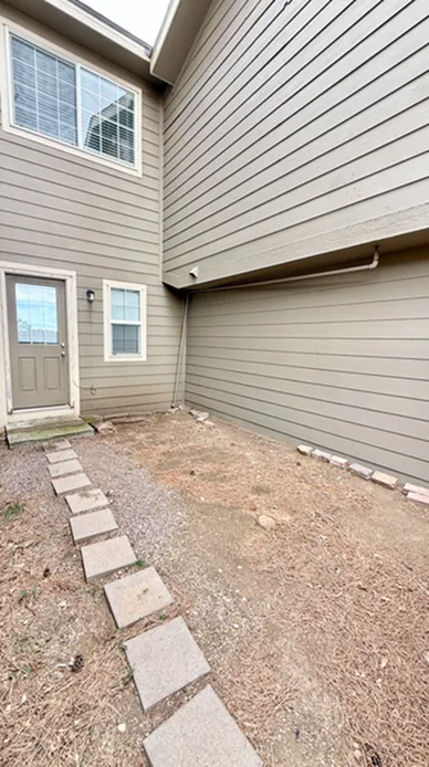 Inviting patio area with a clean exterior, modern windows, and a charming walkway, perfect for outdoor relaxation.